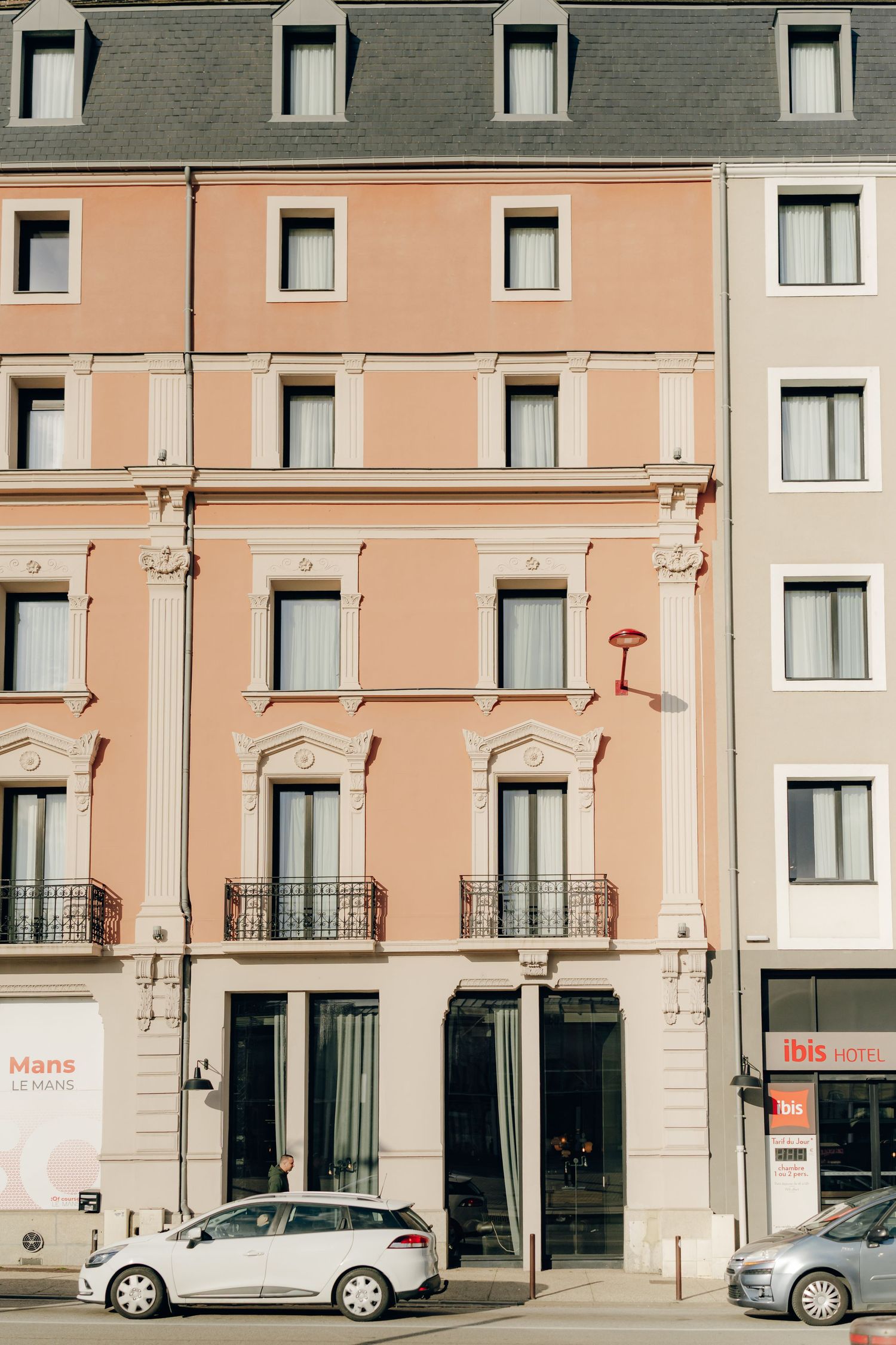Vintage style apartment building facade with peach-colored walls and wrought iron balconies on a city street.