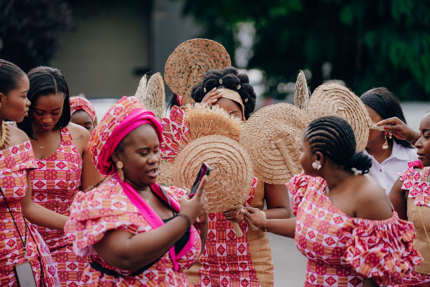 Guests in pink and coral traditional attire dancing and celebrating at an outdoor event.