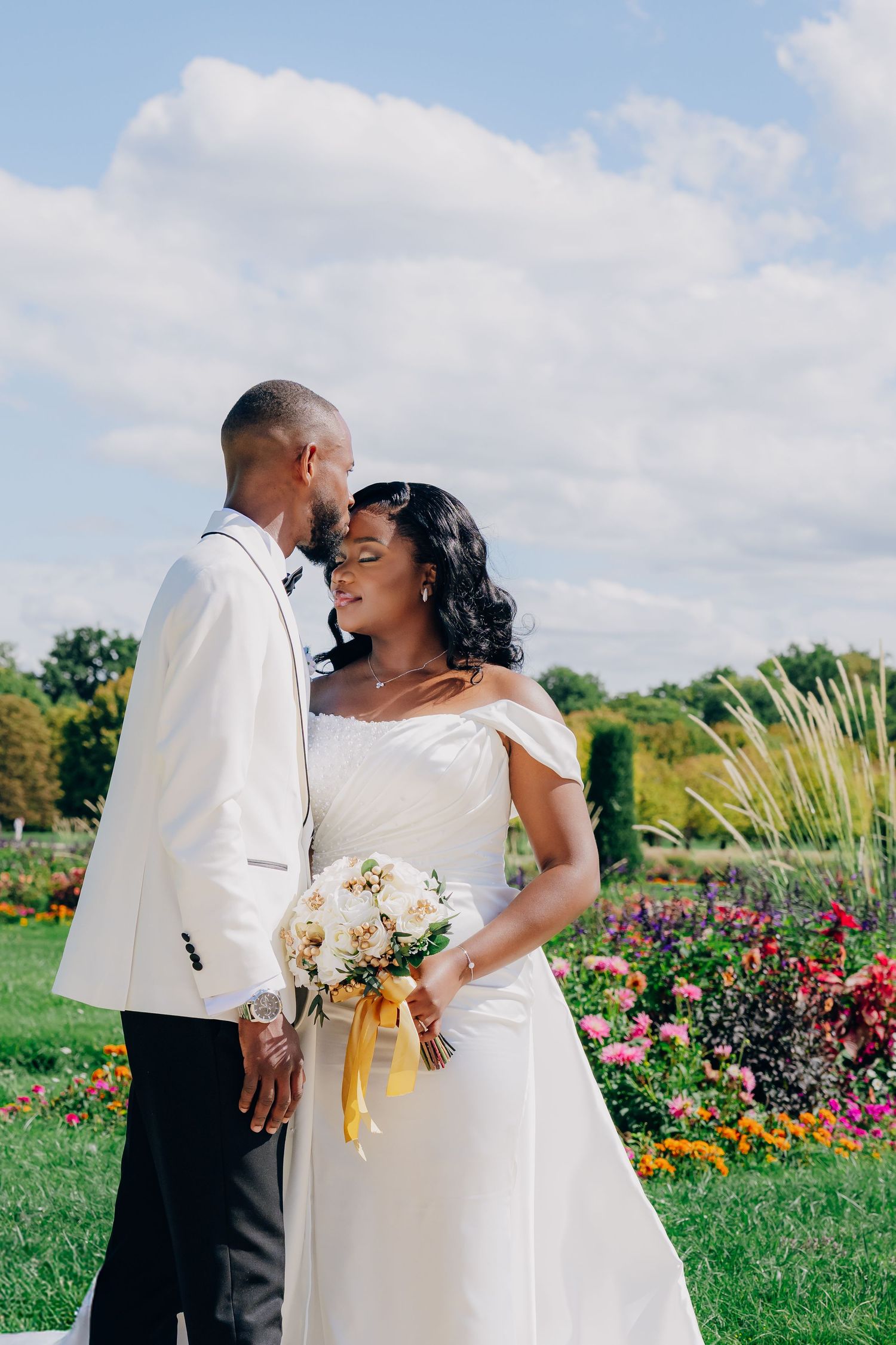 A newlywed couple shares joyful moments together in a vibrant garden filled with colorful flowers.