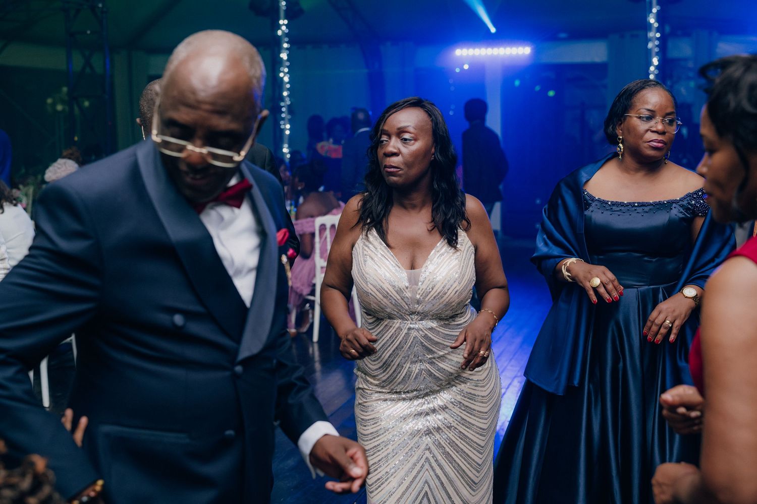 Wedding reception dance party with dramatic blue lighting and festive atmosphere.
