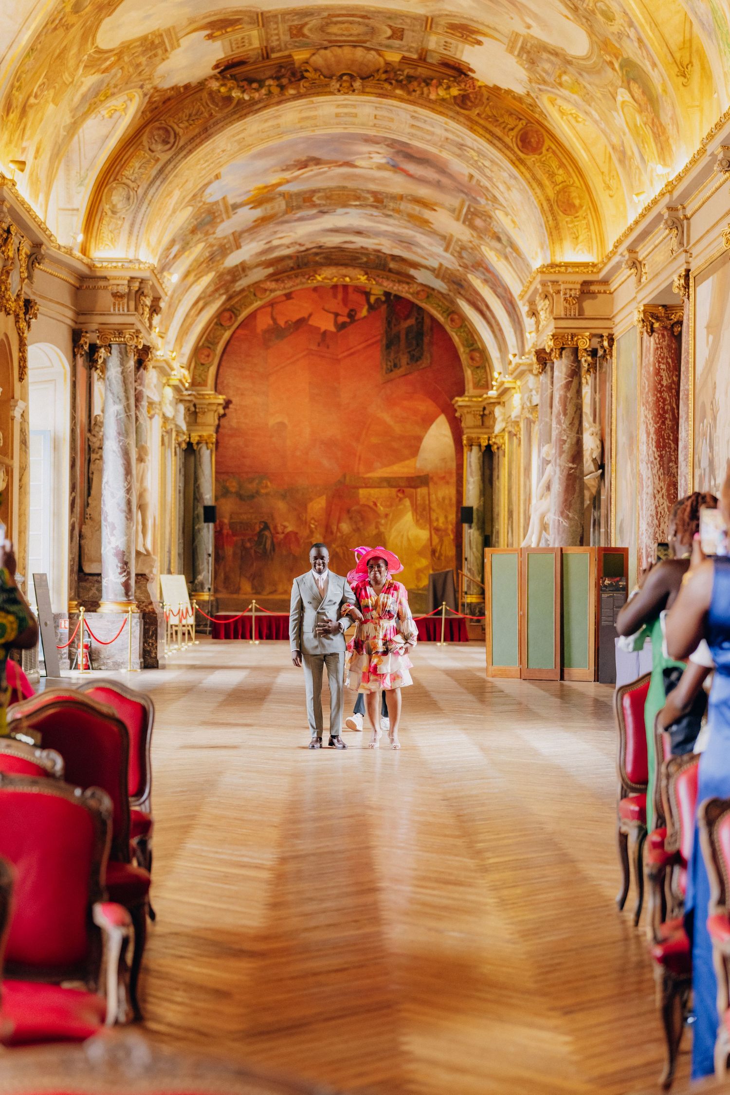 Elegant baroque palace interior with ornate ceiling frescoes, golden details and polished wooden floors.