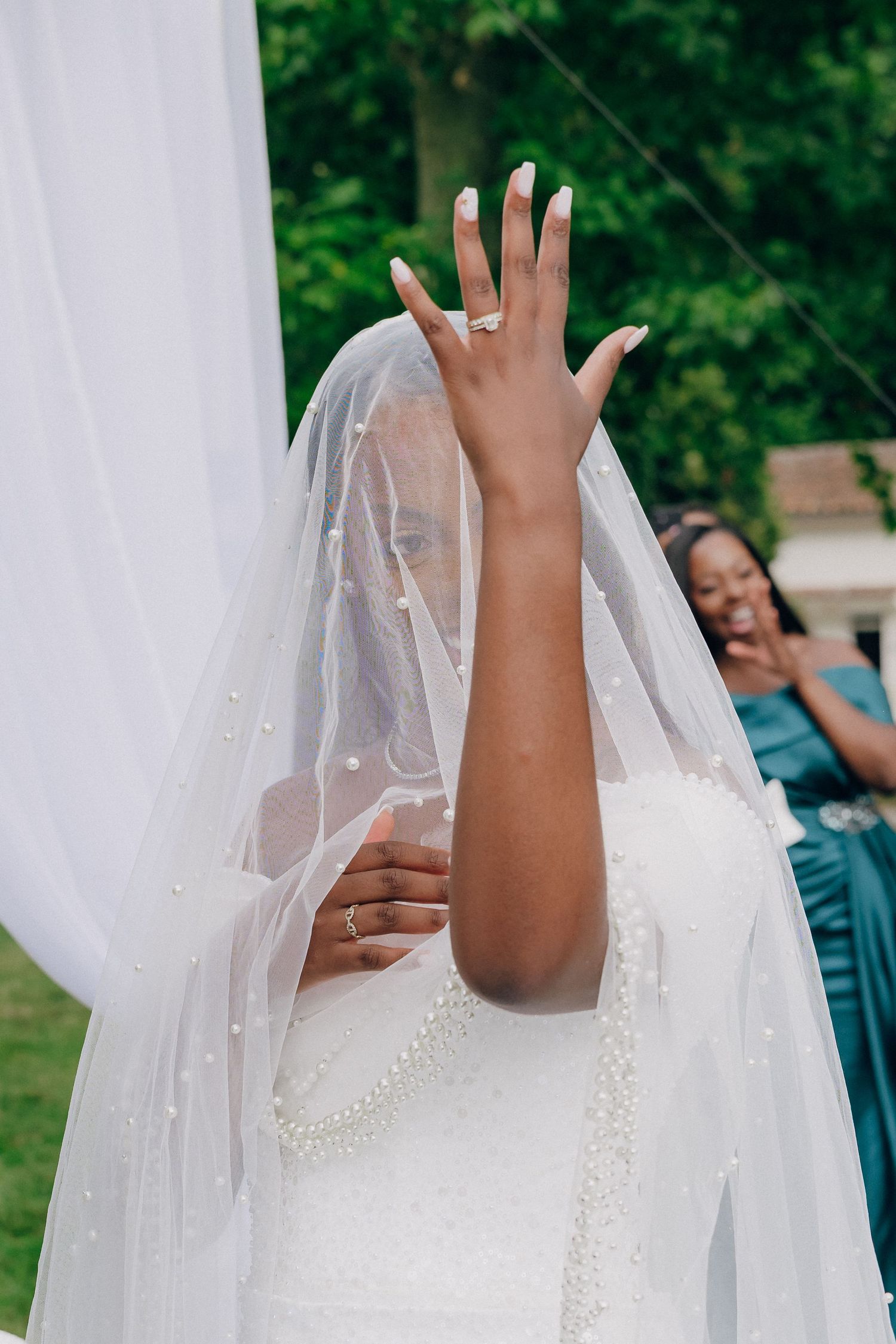 Close-up of a bride's veil with pearl details during an outdoor wedding ceremony.