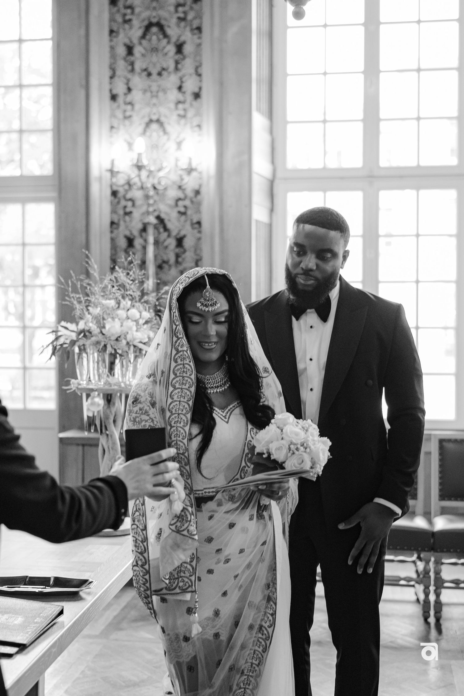 Black and white photo of couple signing wedding documents in elegant room.