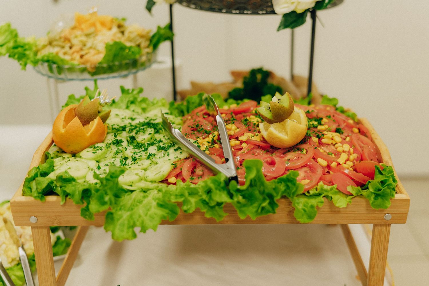 Wooden platter topped with fresh lettuce, sliced salmon, lemons and garnishes served at a catering event.