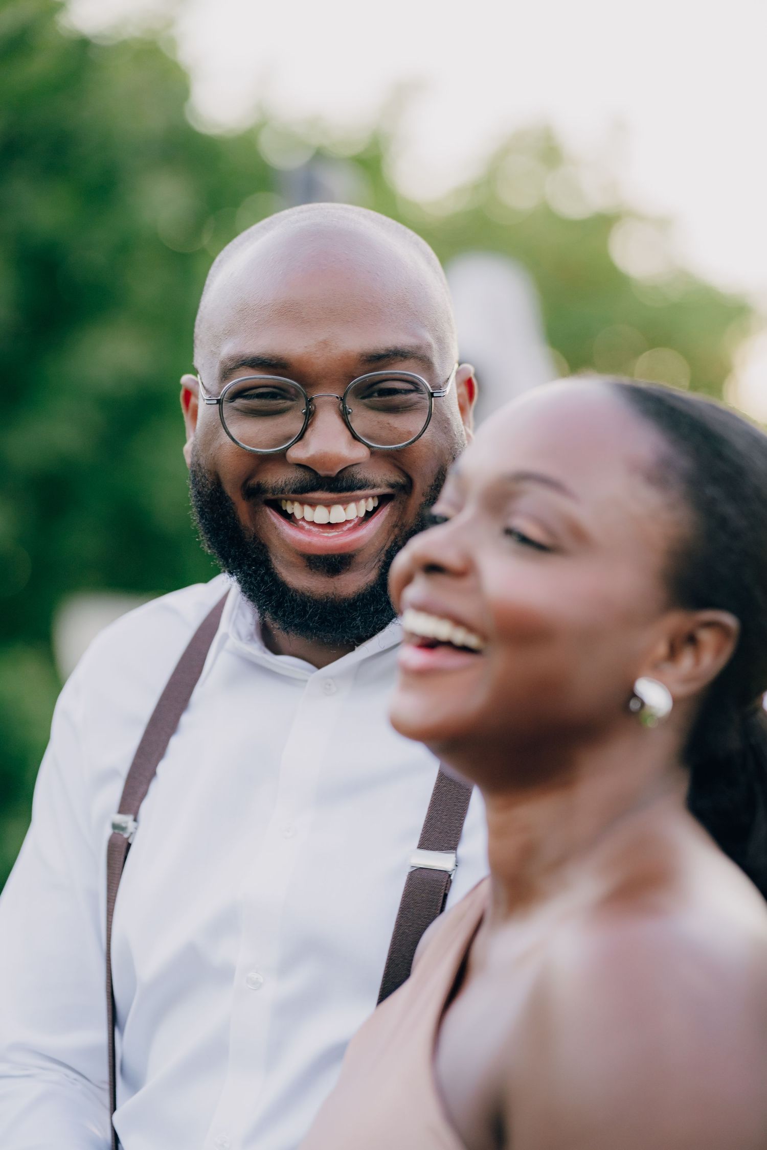 A joyful couple sharing a candid moment outdoors in formal attire.