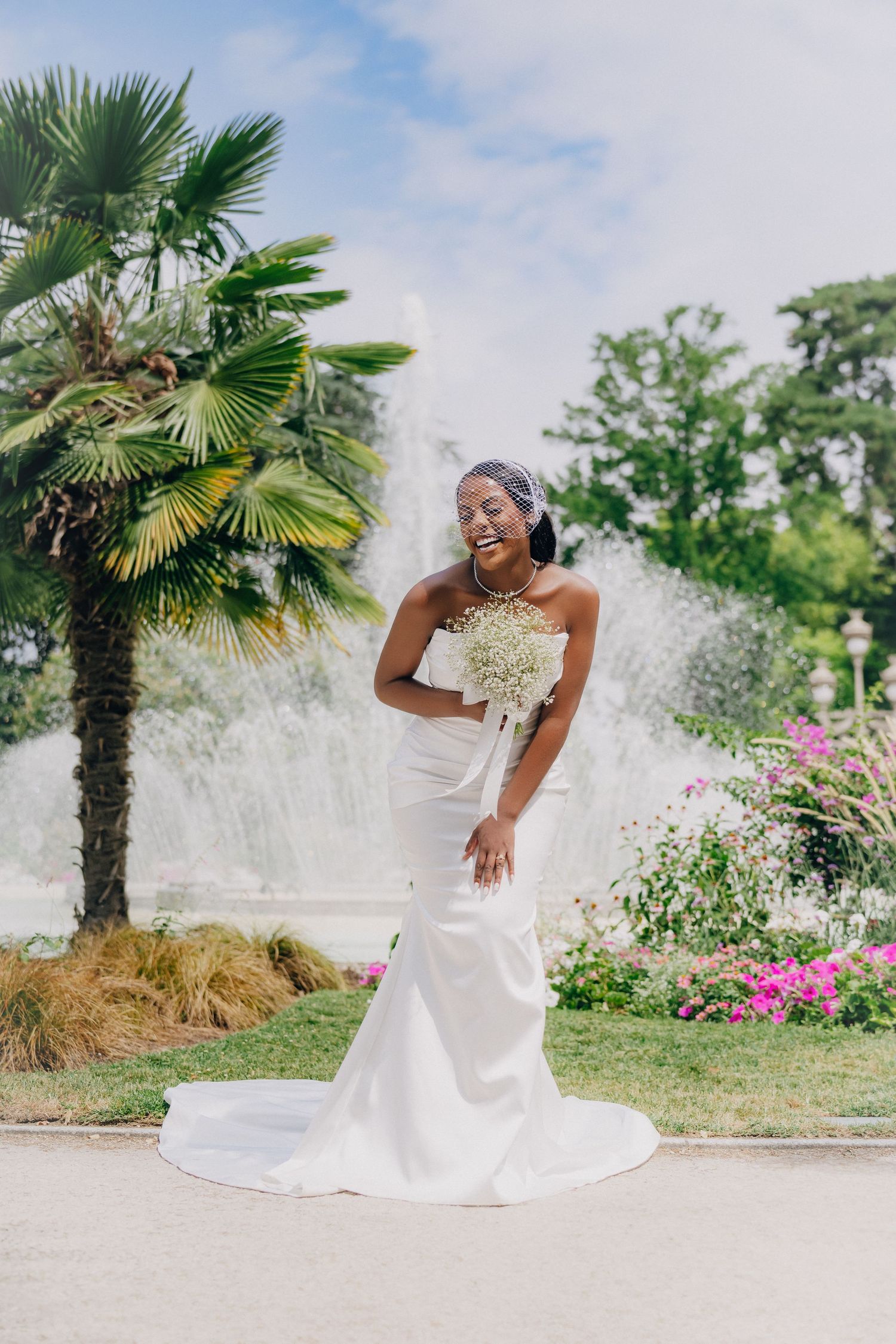 A beautiful bridal portrait series in a garden setting with palm trees and pink flowers in the background.