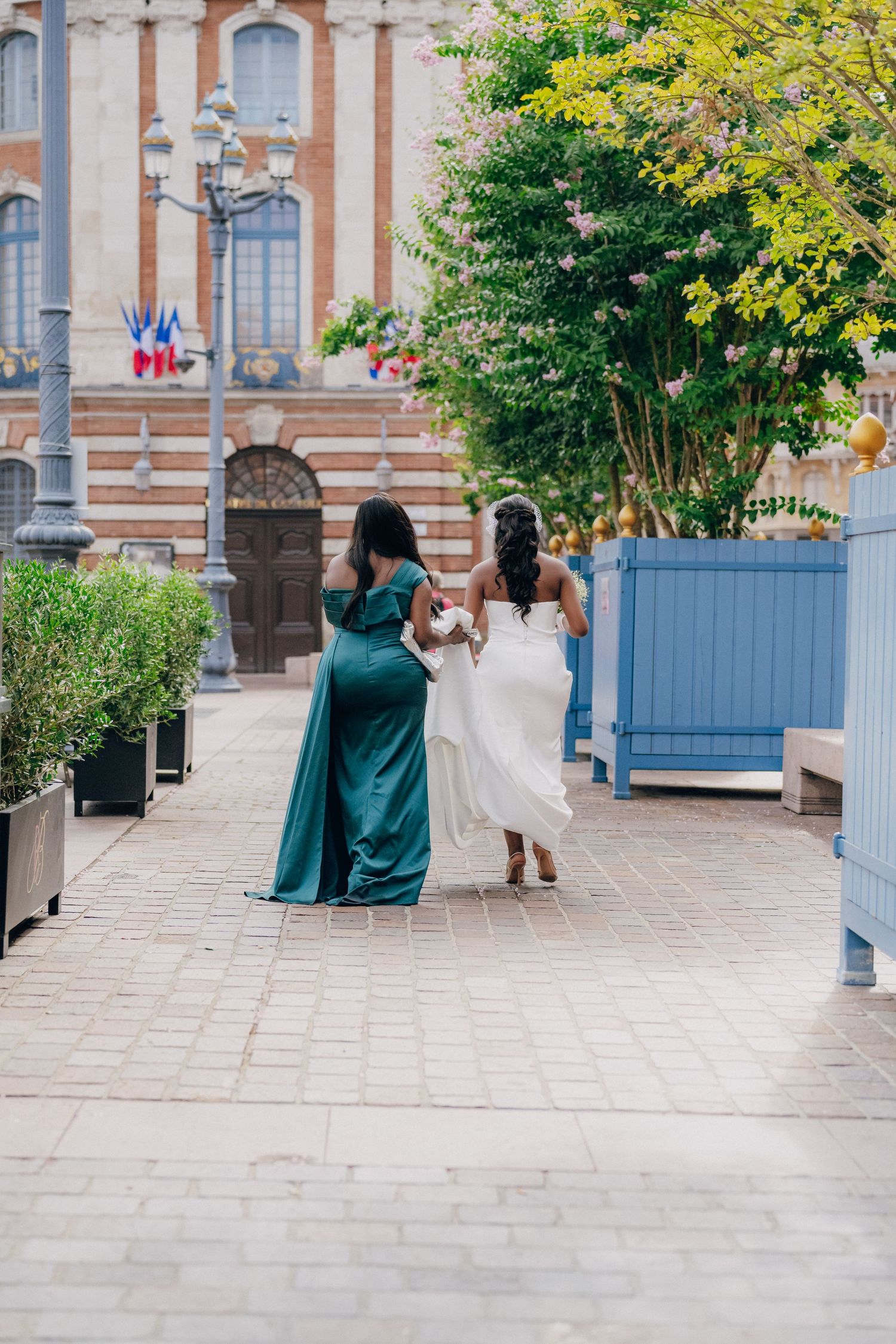 Wedding couple poses in front of a historic building with elegant blue doors and stone architecture.