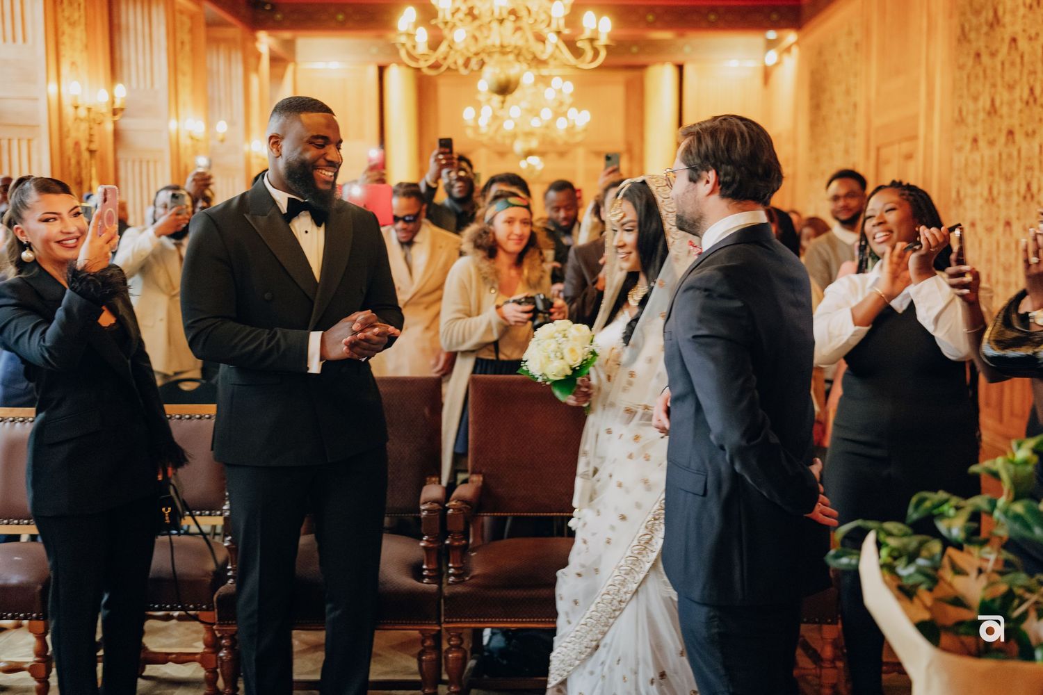 A joyous celebration in an ornate wedding venue with guests applauding the newlyweds.