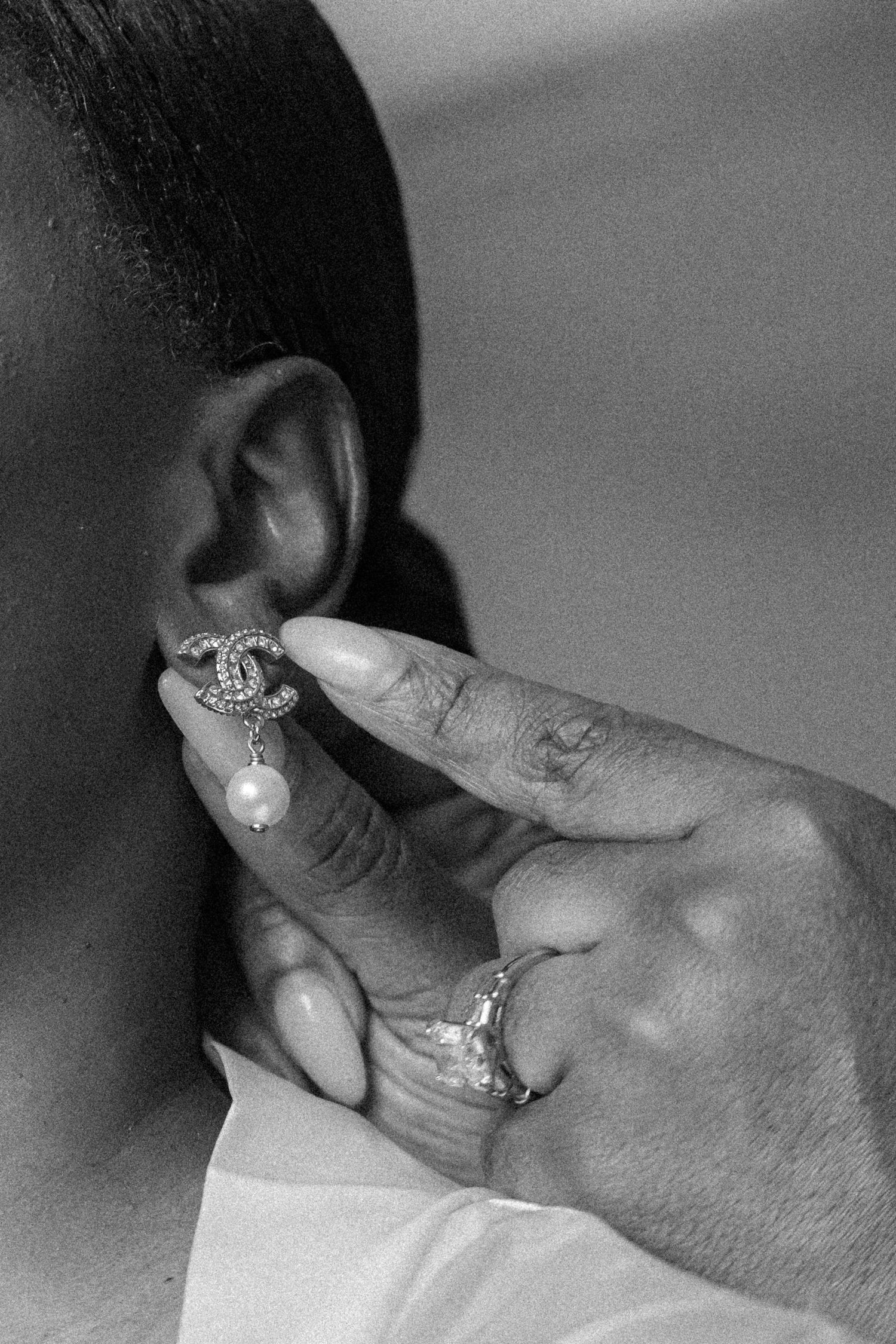 A black and white close-up sequence showing hands placing a pearl into a piece of jewelry.