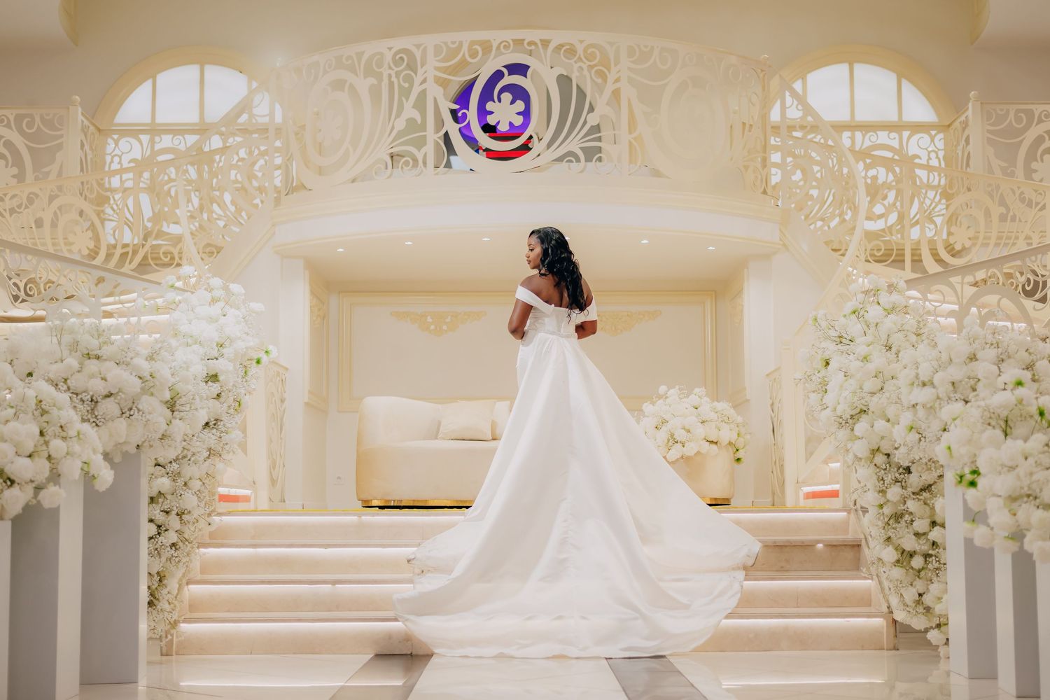 Elegant wedding ceremony setup with ornate white floral archway and decorative details in a grand ballroom.
