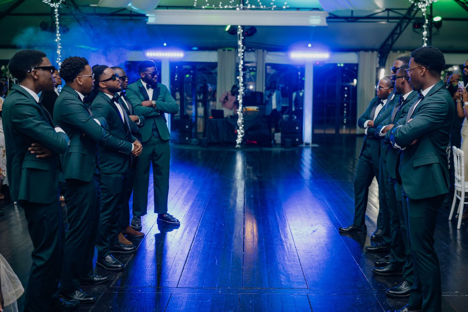 Wedding guests lined up on dance floor with blue and green ambient lighting.