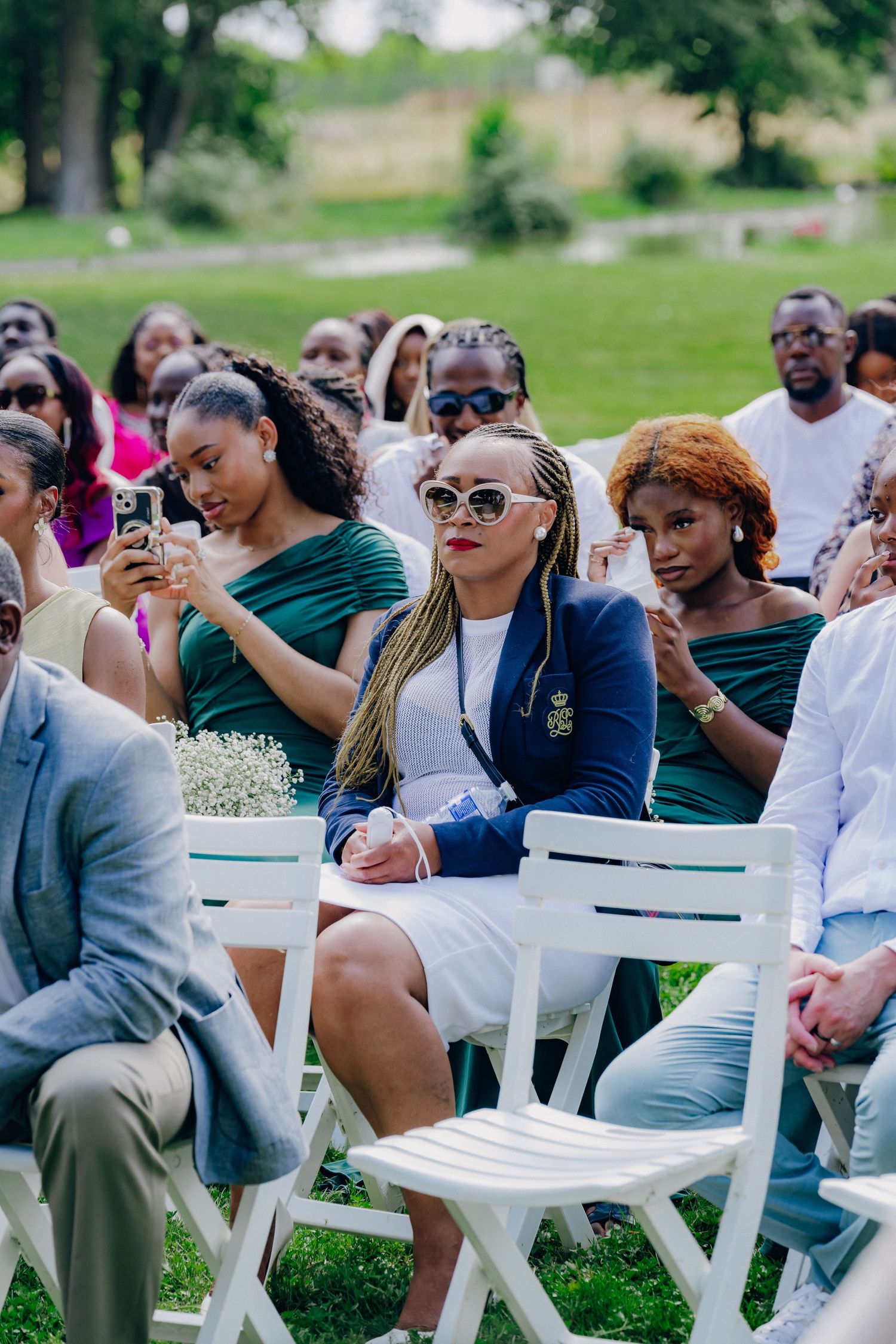 Attendees in casual attire seated in rows of white chairs at an outdoor event.