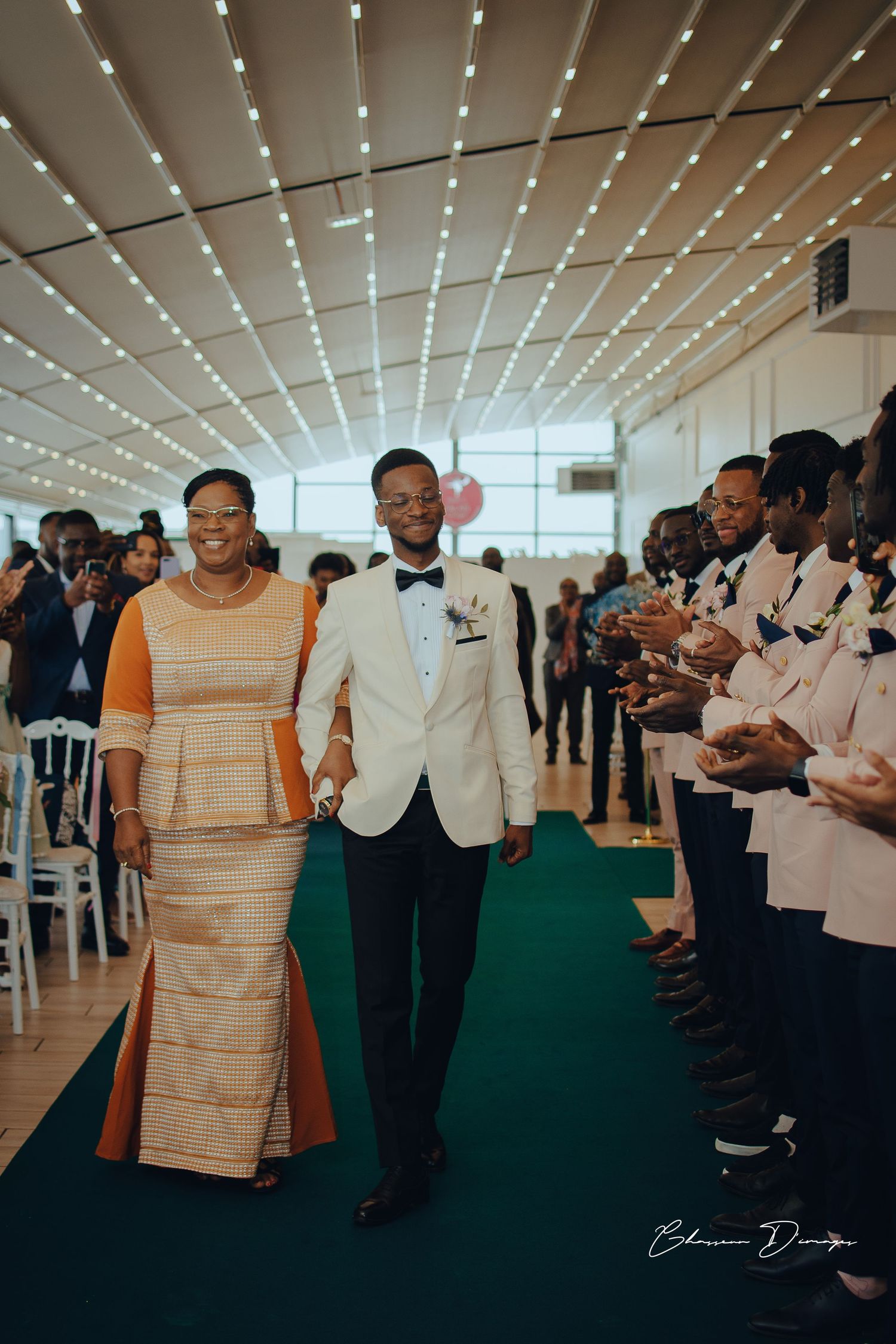 Wedding processional in venue with stunning ceiling lights and green carpet.