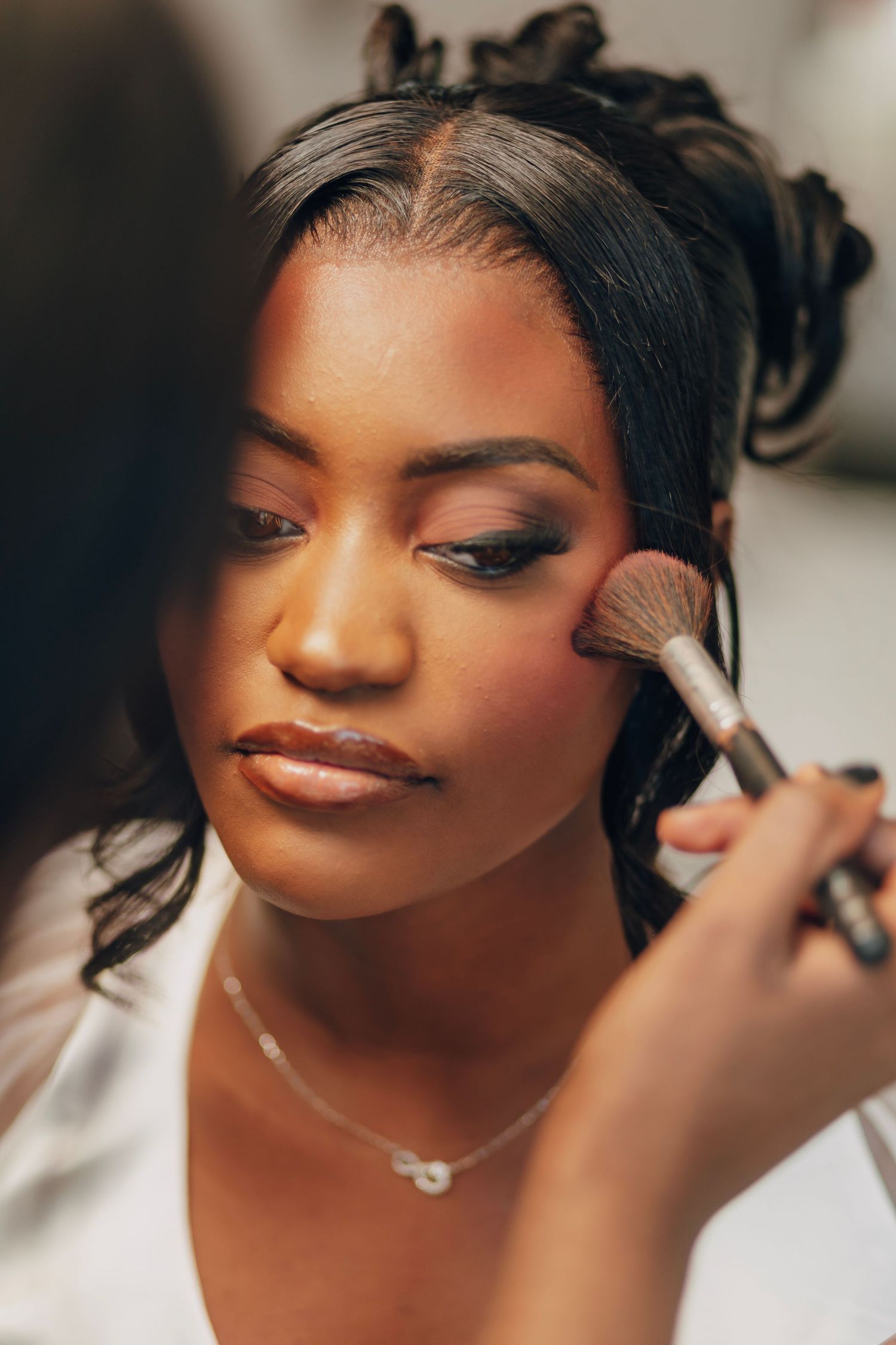 Behind-the-scenes shot of wedding makeup application with professional brush.
