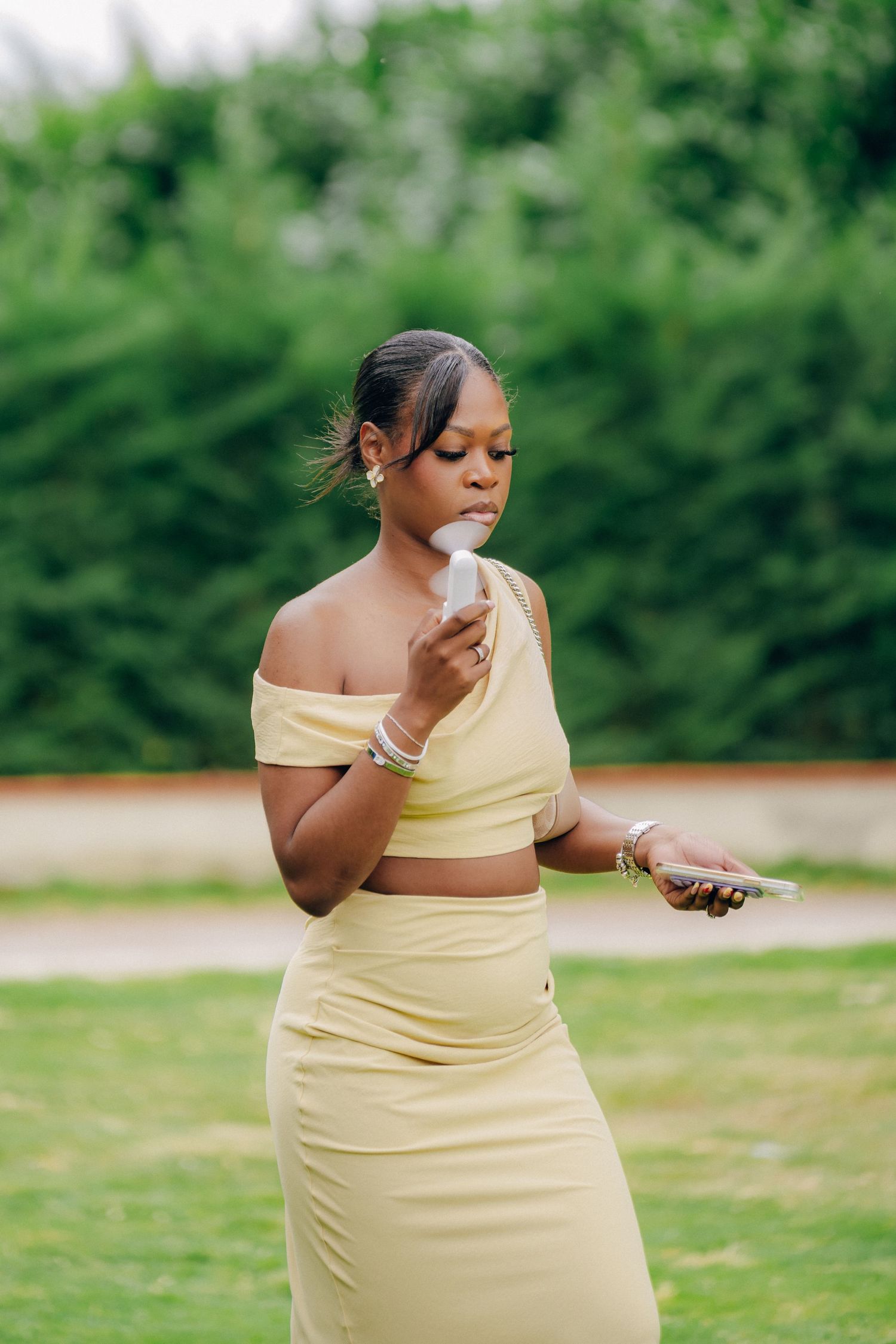 A person in a yellow two-piece outfit stands outdoors against a green background.