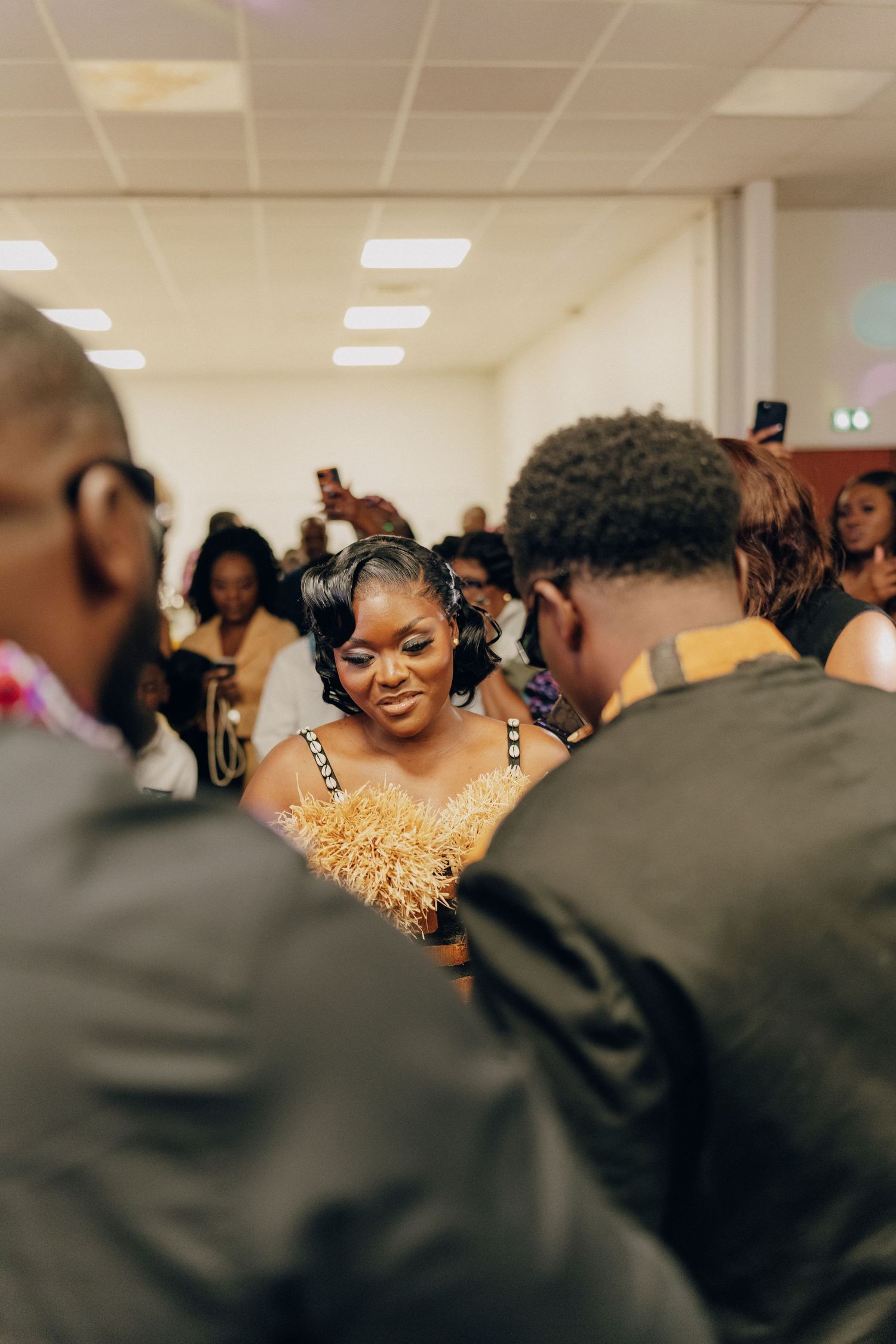 A joyful celebration scene with people gathered around wearing formal attire in a brightly lit room.