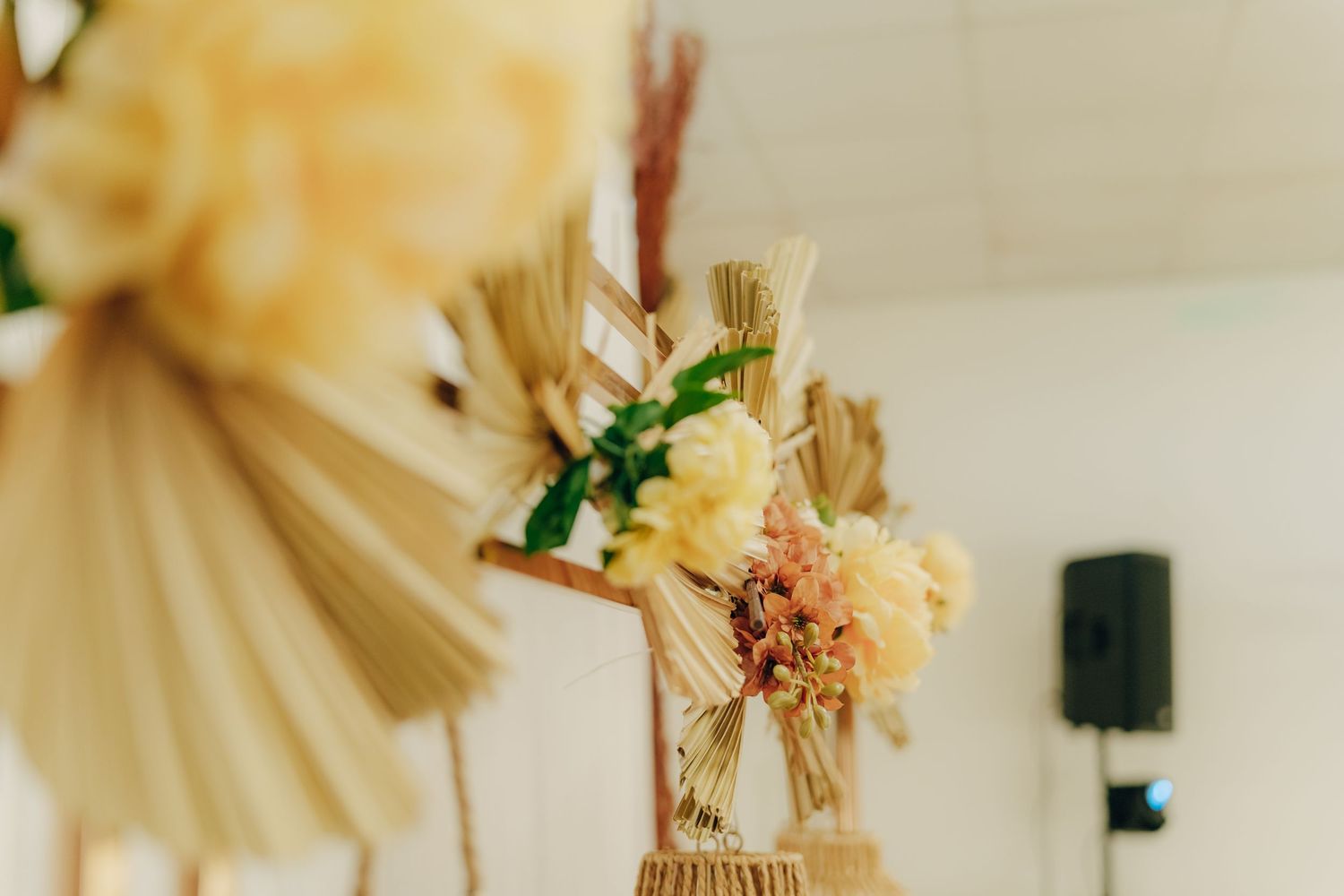 Blurred close-up view of wheat stalks and dried flower decorations in soft beige tones against a light background.