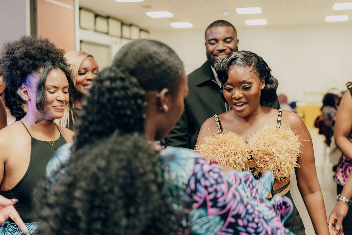 A group of people smile and laugh together at a joyous indoor celebration gathering.