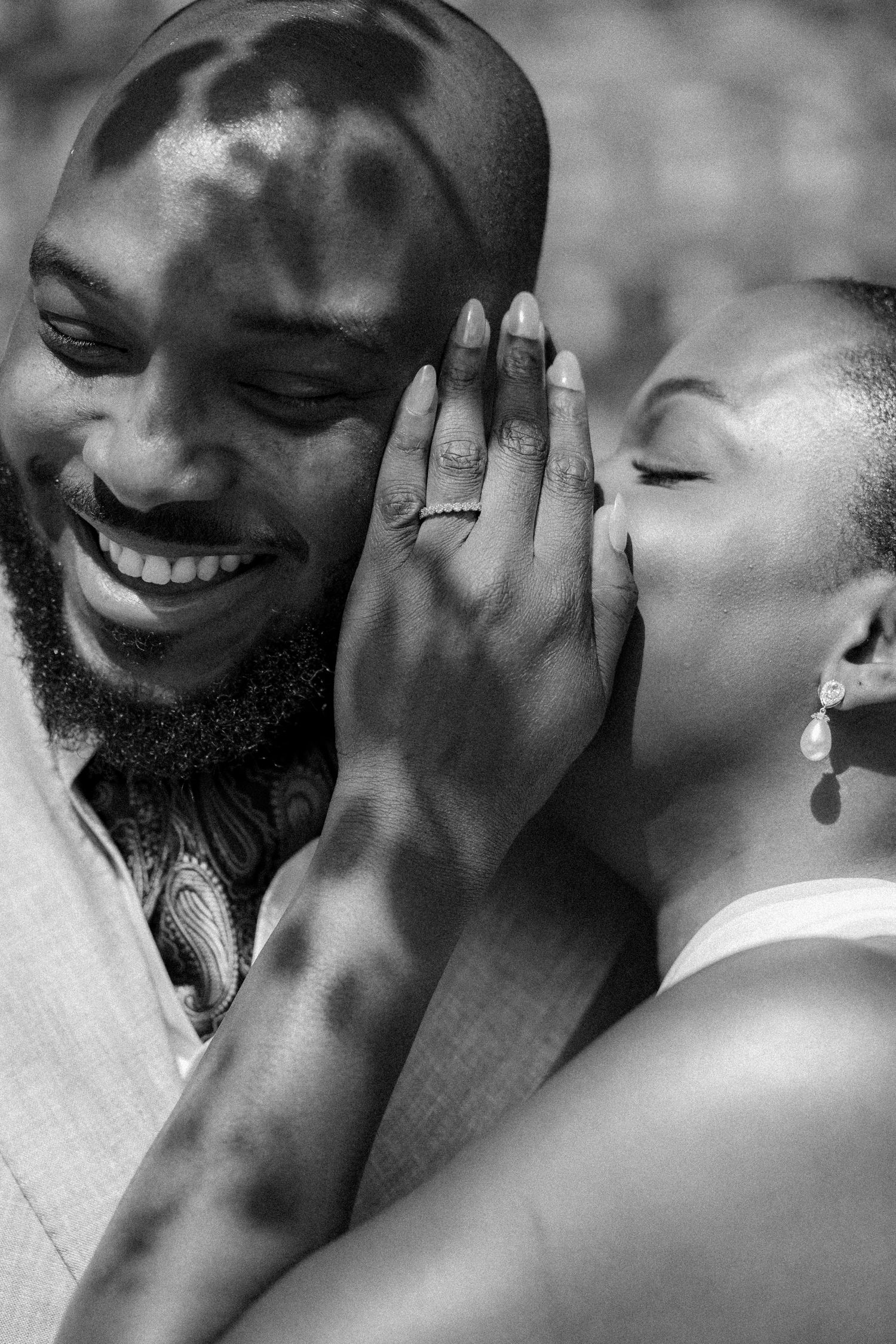 A tender black and white portrait of a couple sharing an intimate moment as they smile and embrace.