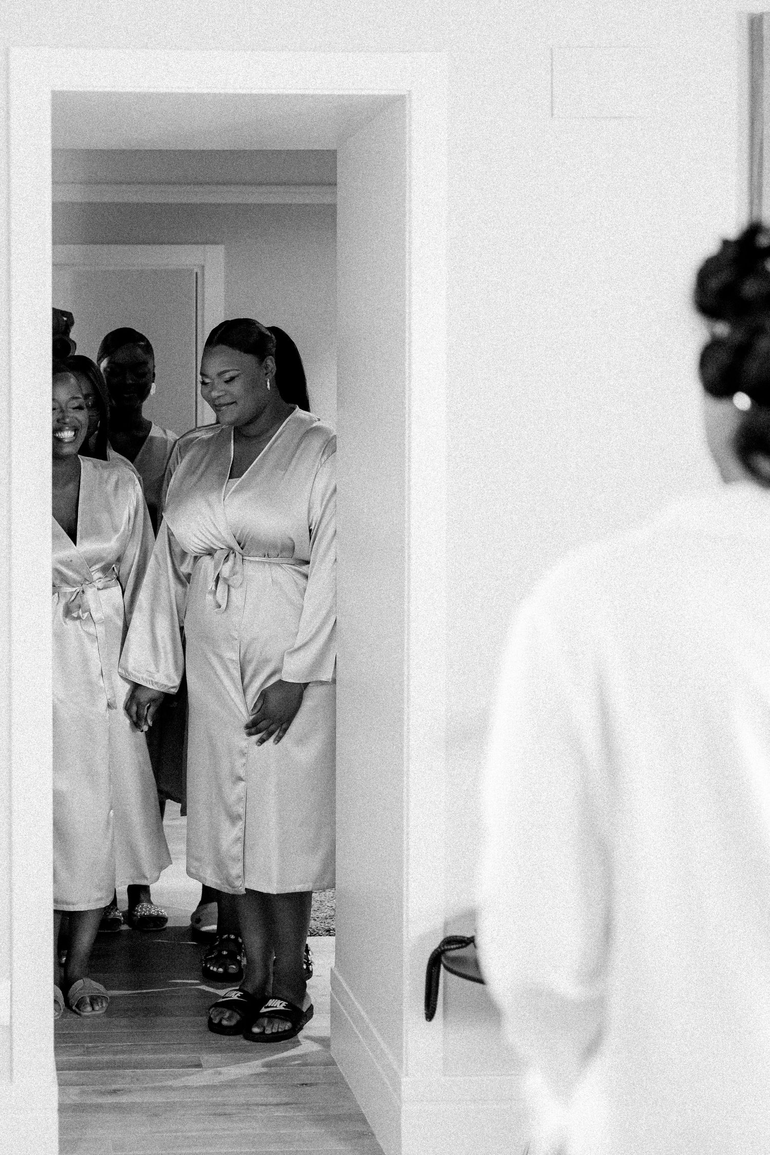 Black and white photograph of wedding preparation in a bright hallway.