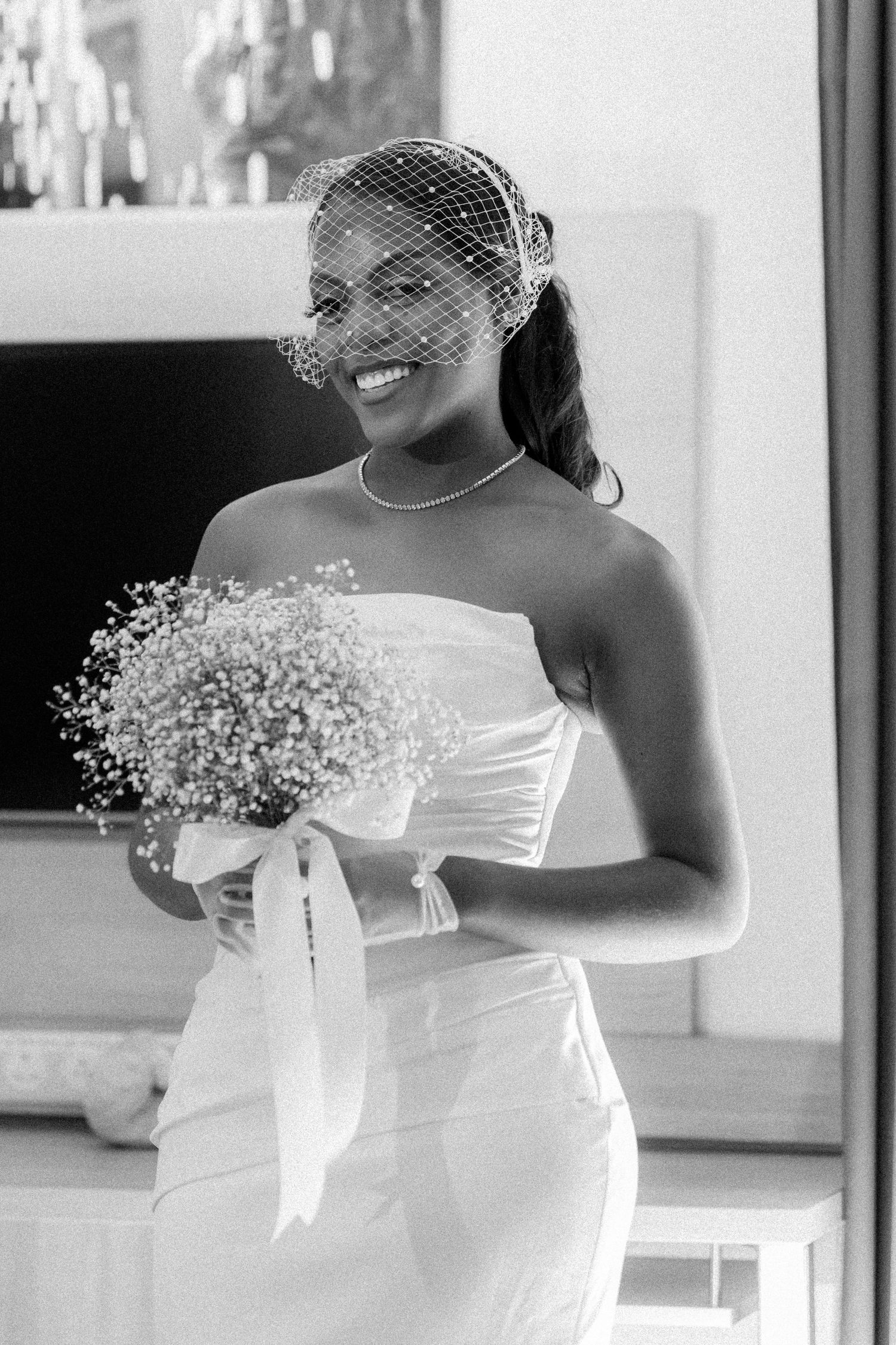 Wedding party members in white strapless dresses holding baby's breath bouquets.