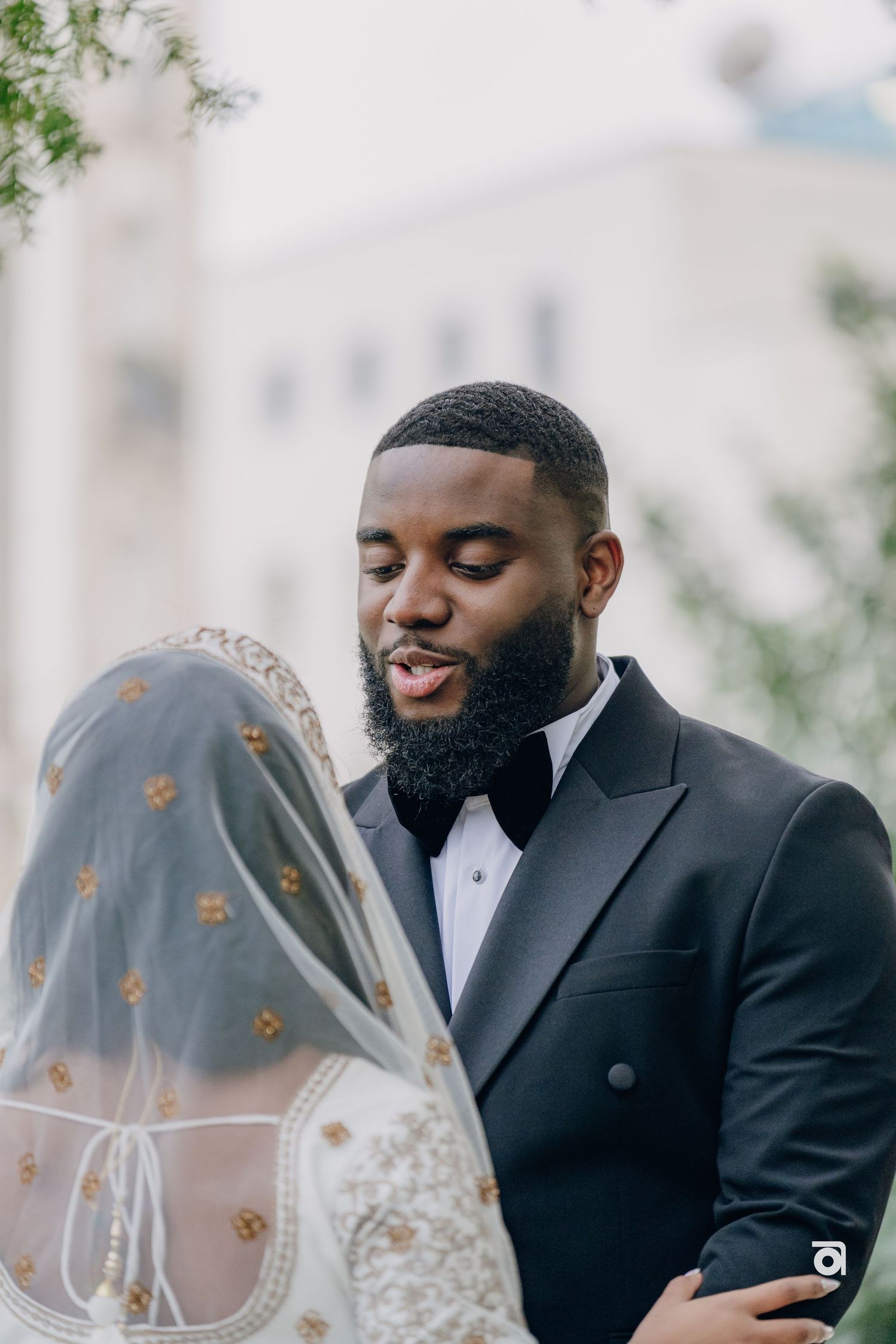 A wedding couple sharing a tender moment in formal attire with the bride wearing a sheer veil.