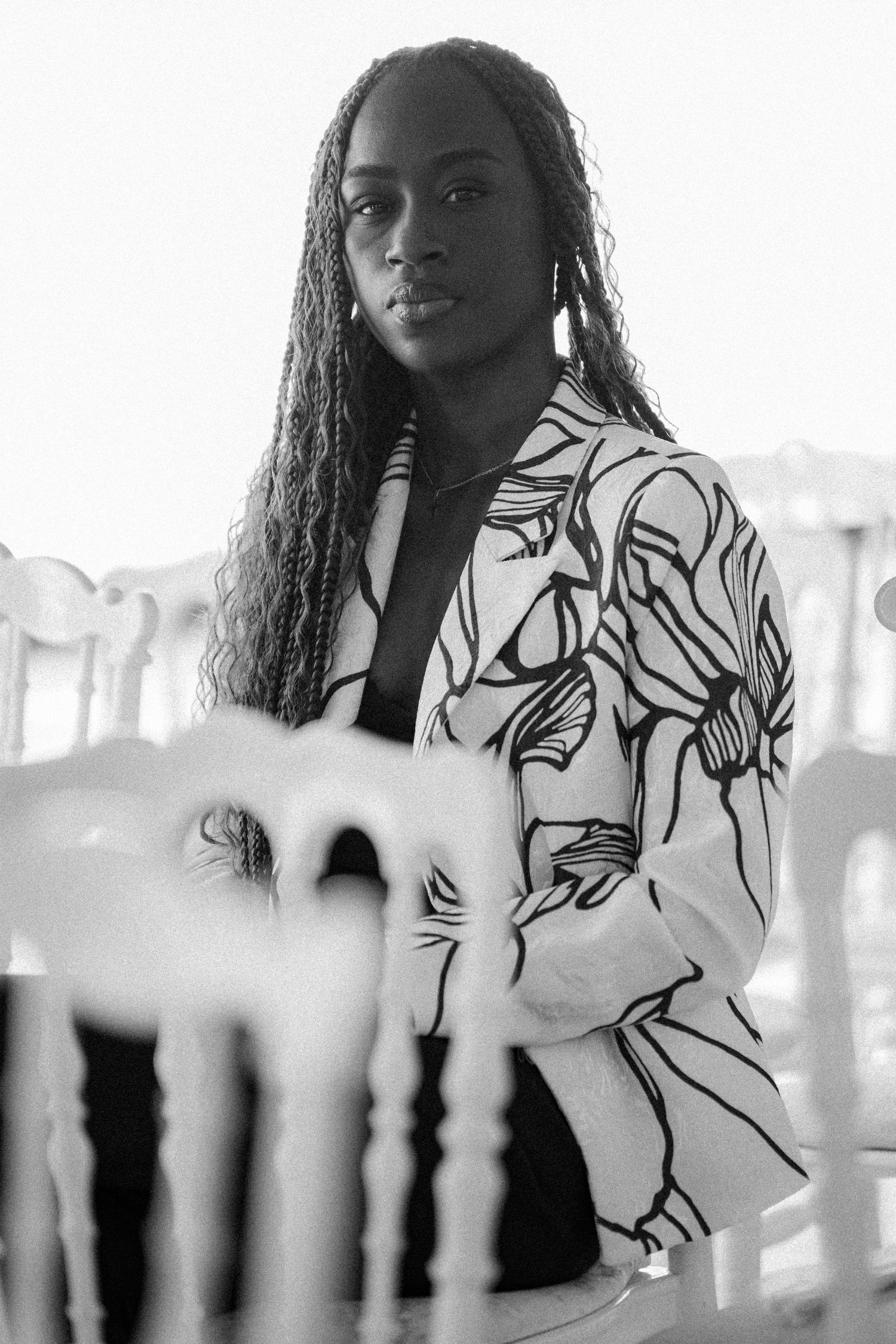 A black and white portrait featuring a person wearing a floral patterned jacket in an indoor setting.