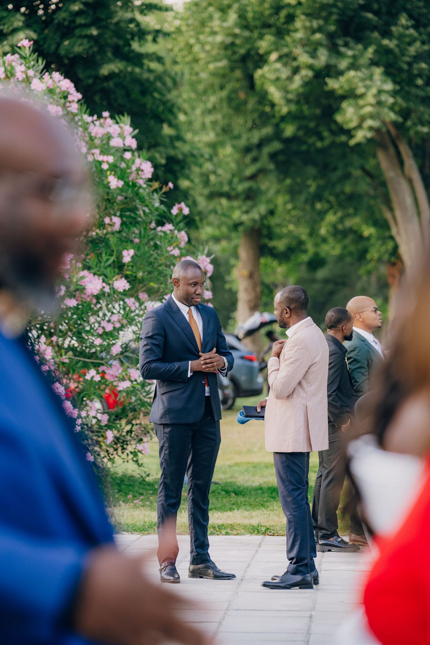 Outdoor wedding gathering with pink roses blooming in garden setting.