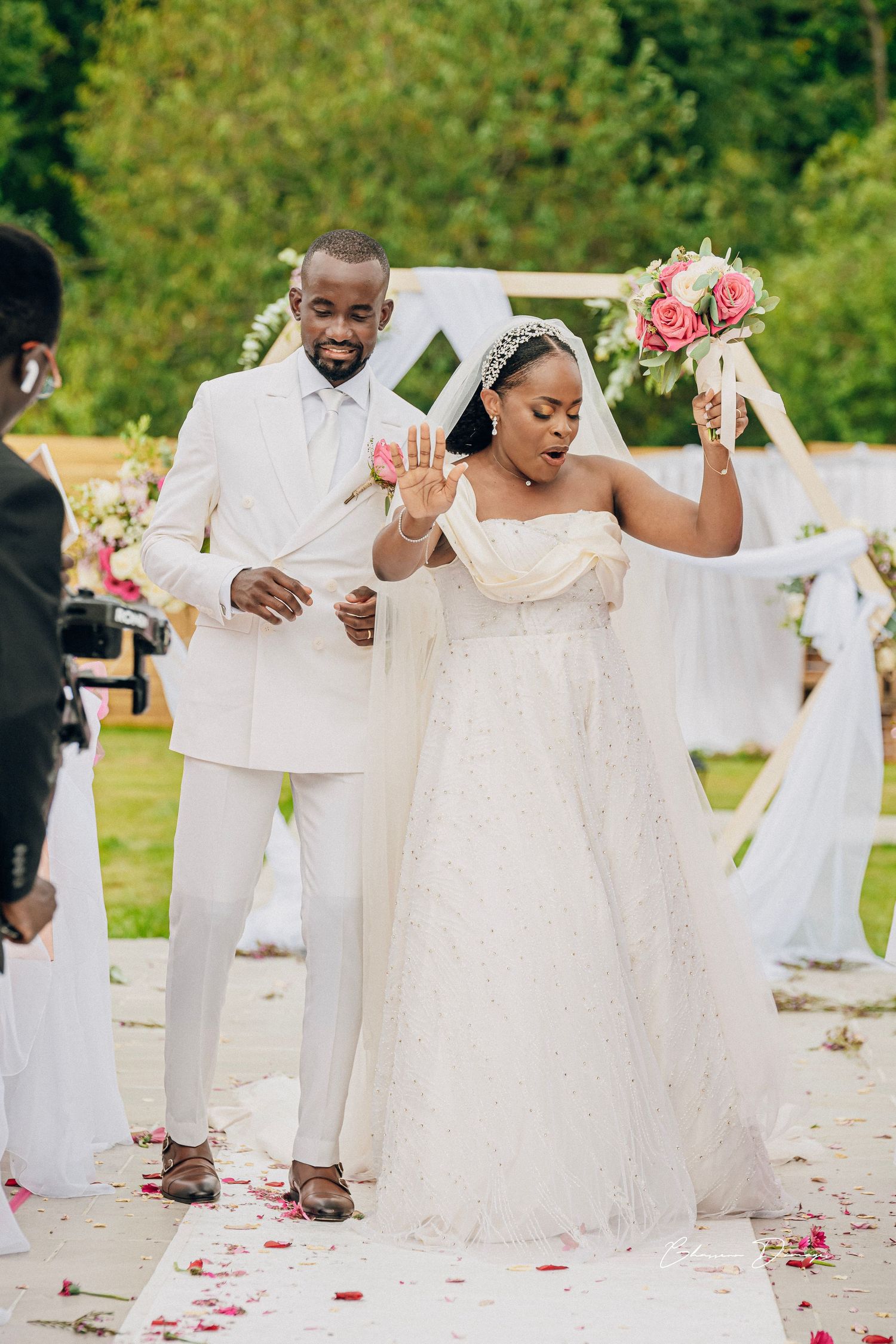 Joyful celebration moment at outdoor wedding with white and pink floral decorations.