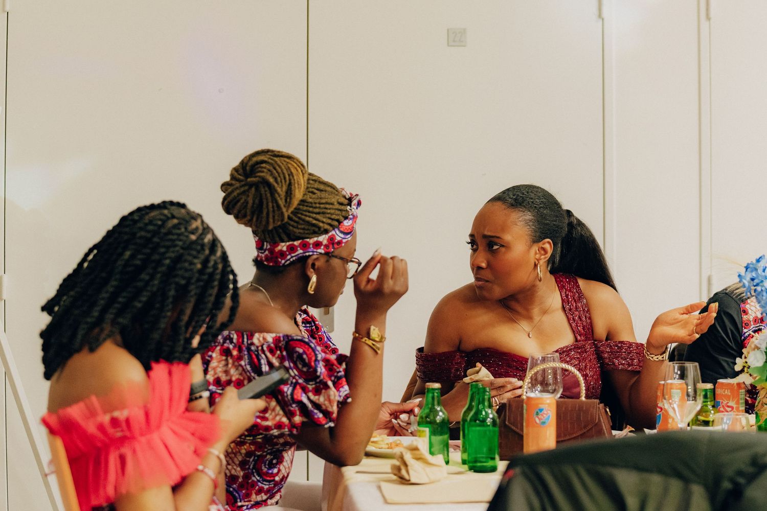 A group of friends enjoy drinks and conversation while sitting together at a table during a social gathering.