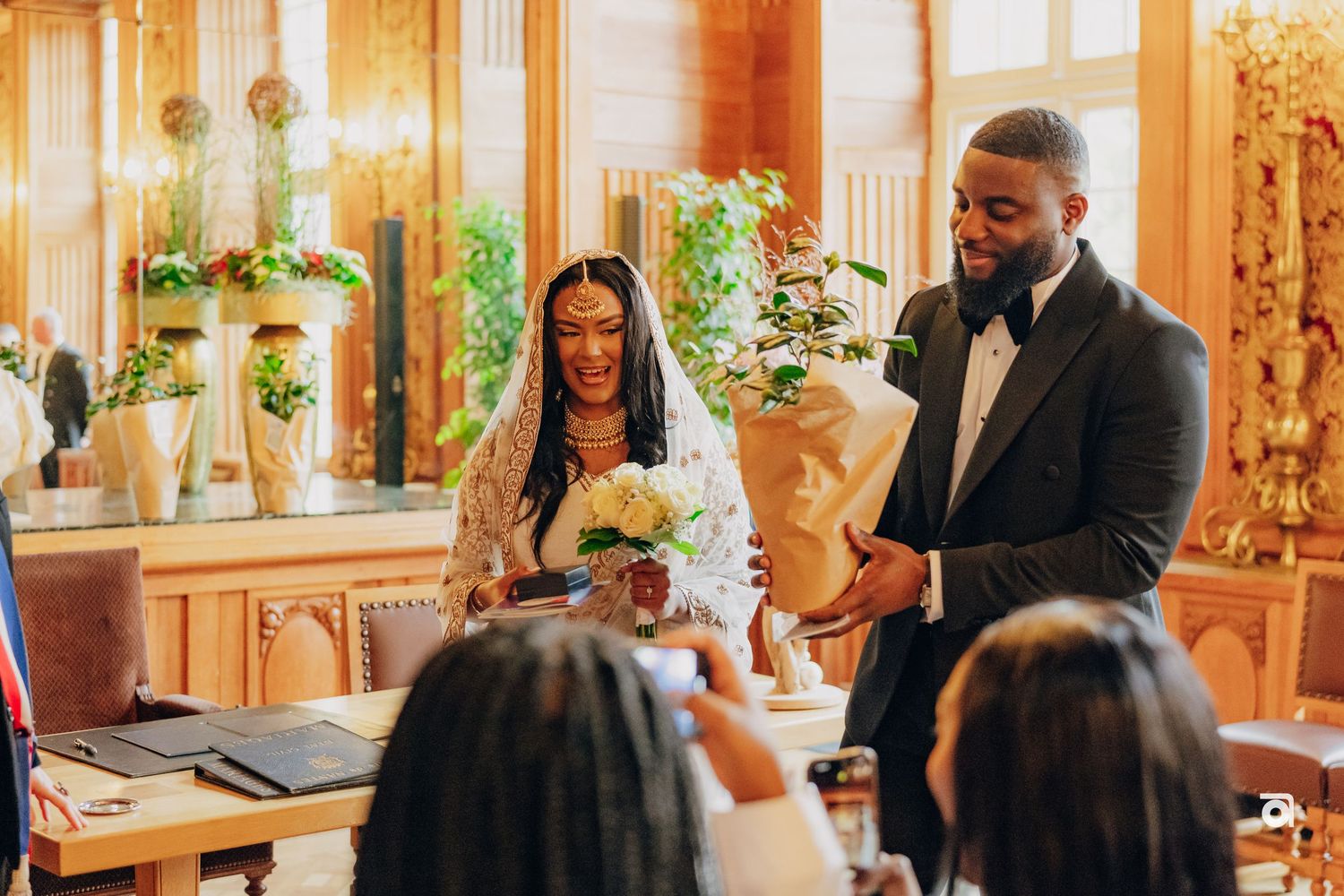 A formal gathering in an elegant ballroom with golden decor and warm lighting.