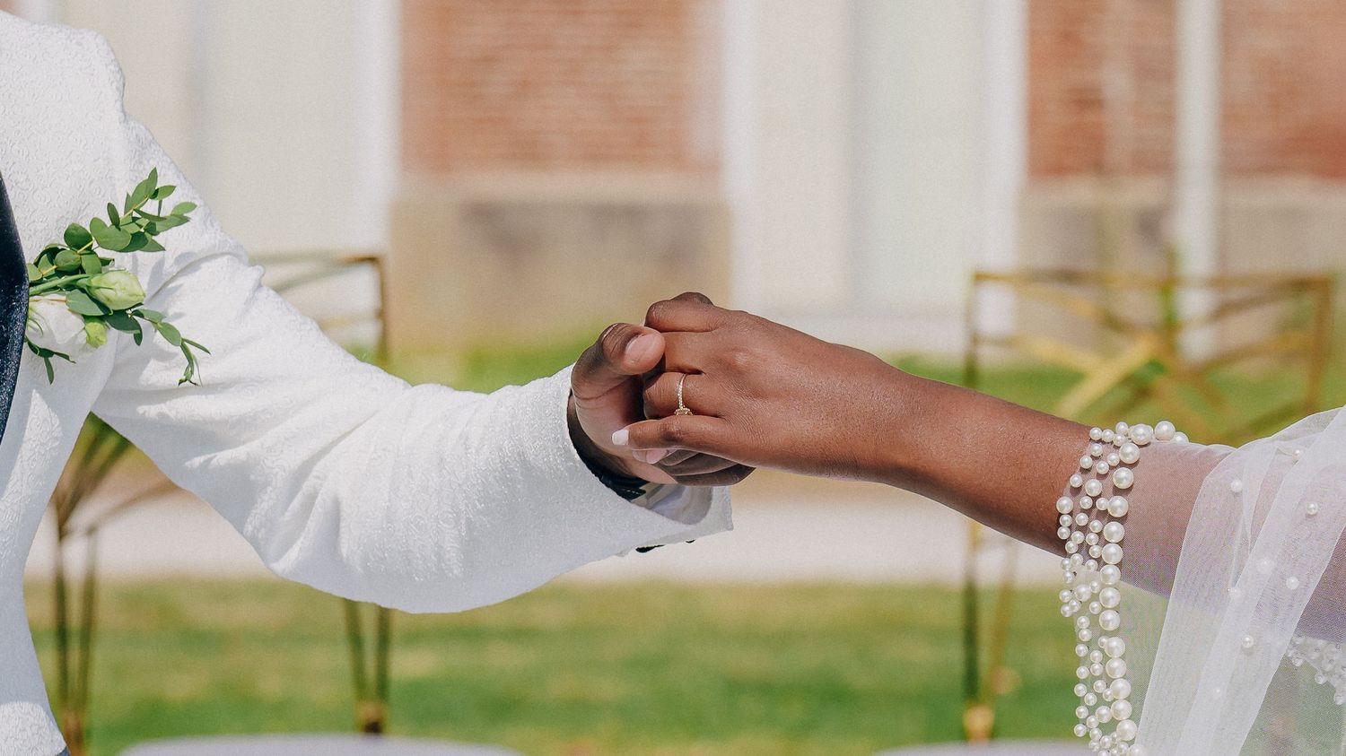 Hands of wedding party members holding champagne glasses in a celebratory toast outdoors.