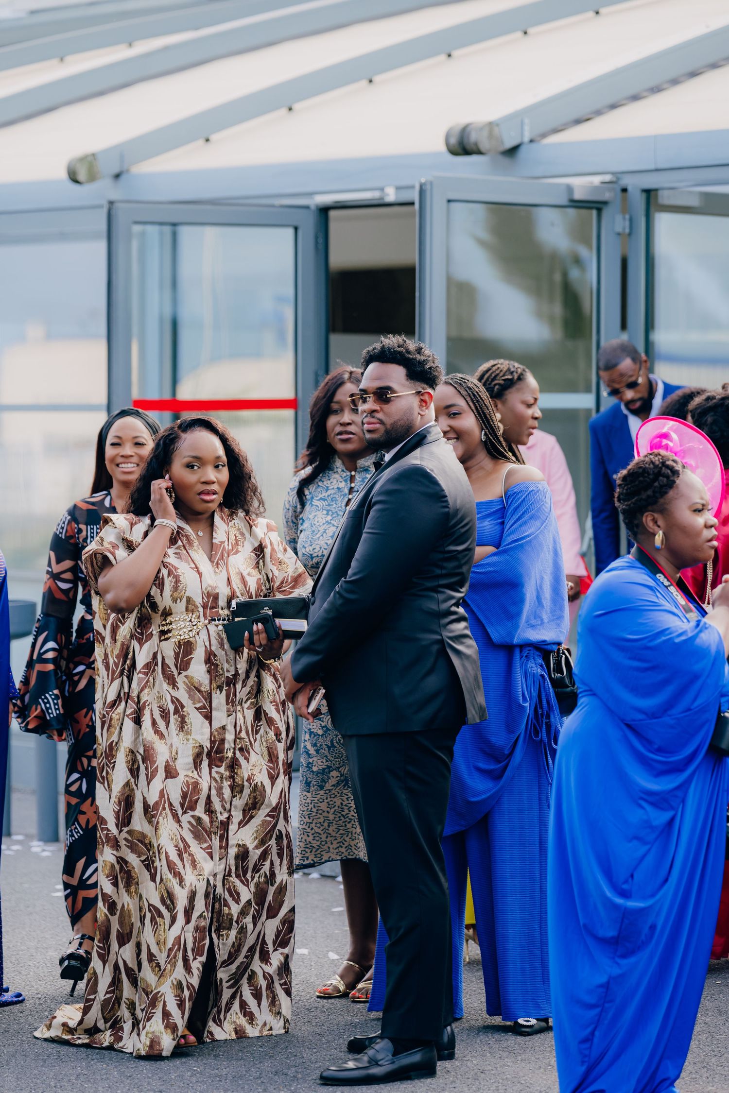 Wedding party members in blue dresses and patterned outfits dance during reception celebrations.