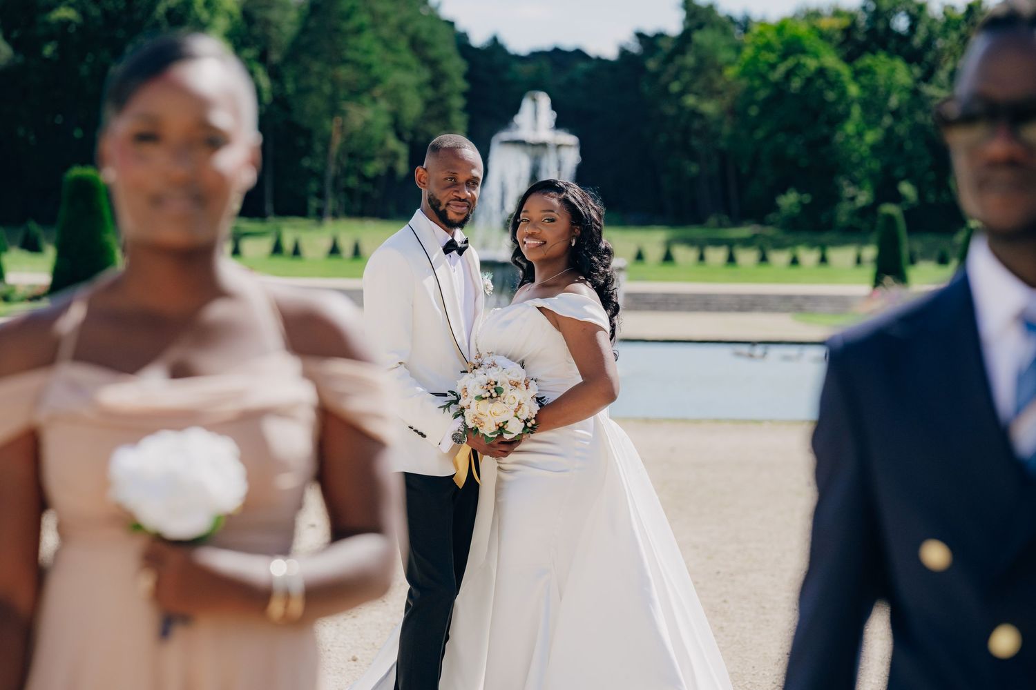 Wedding party poses outdoors with groomsmen in dark suits and bridesmaids in elegant dresses.