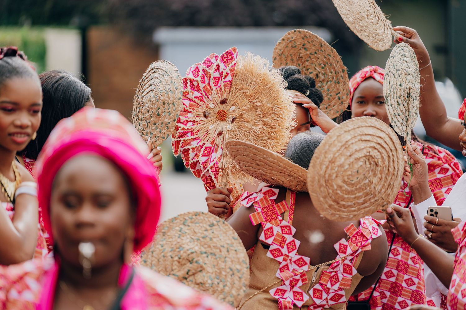 Celebratory crowd waves straw hats decorated with red ribbons during a festive gathering.