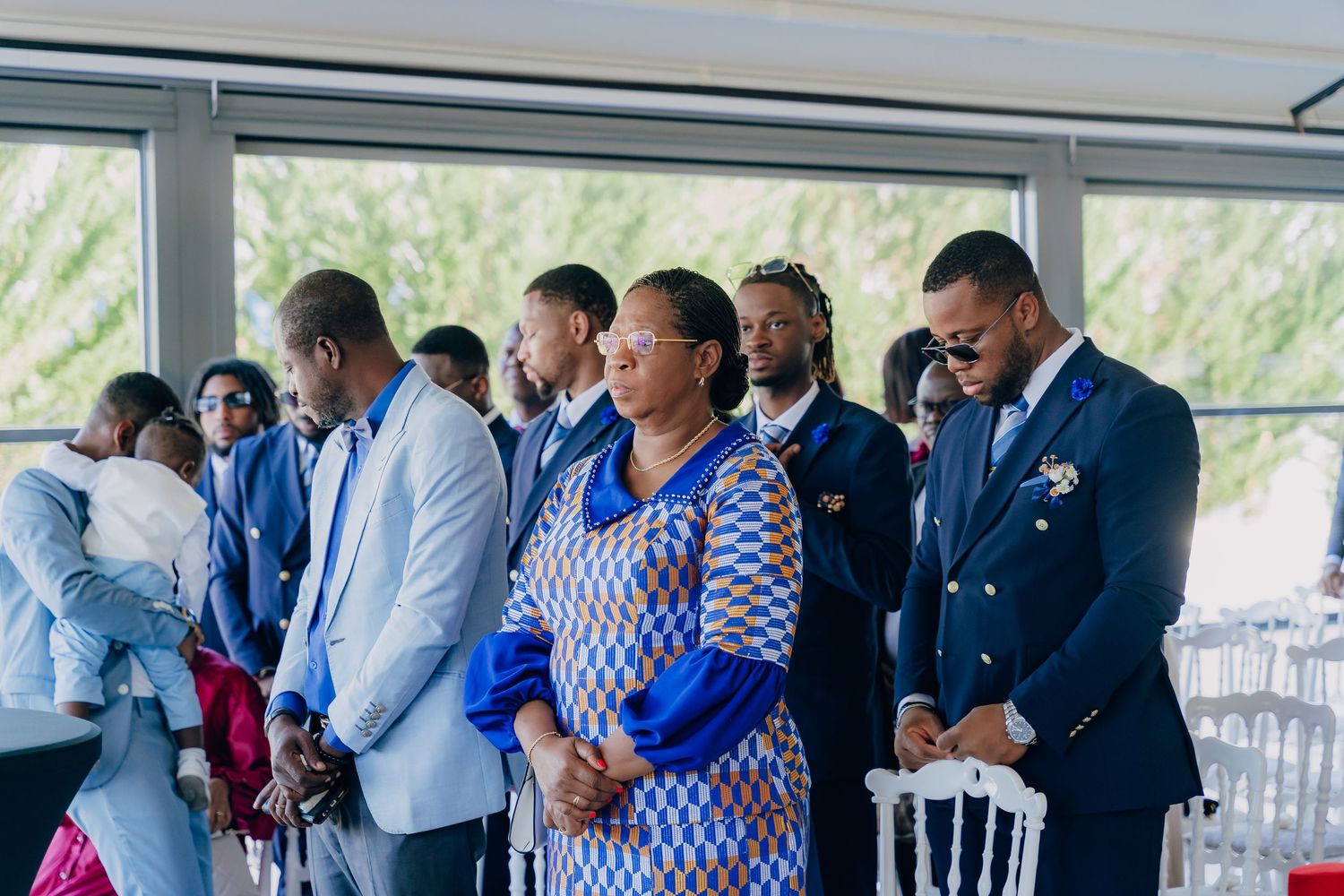 A group of formally dressed people gather in a bright indoor space during what appears to be a social event or function.