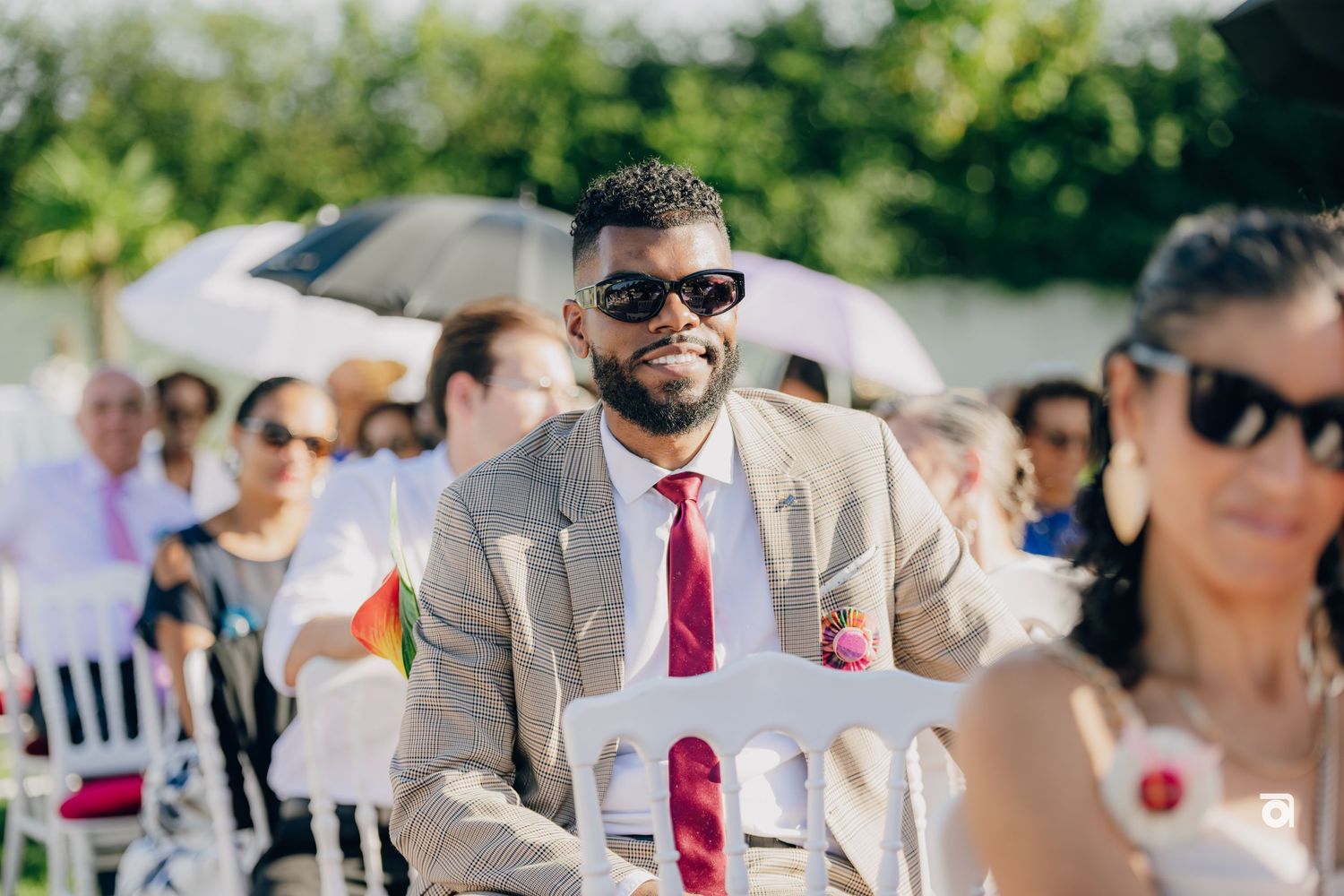 Wedding party members walking under bright sunlight during an outdoor summer ceremony.
