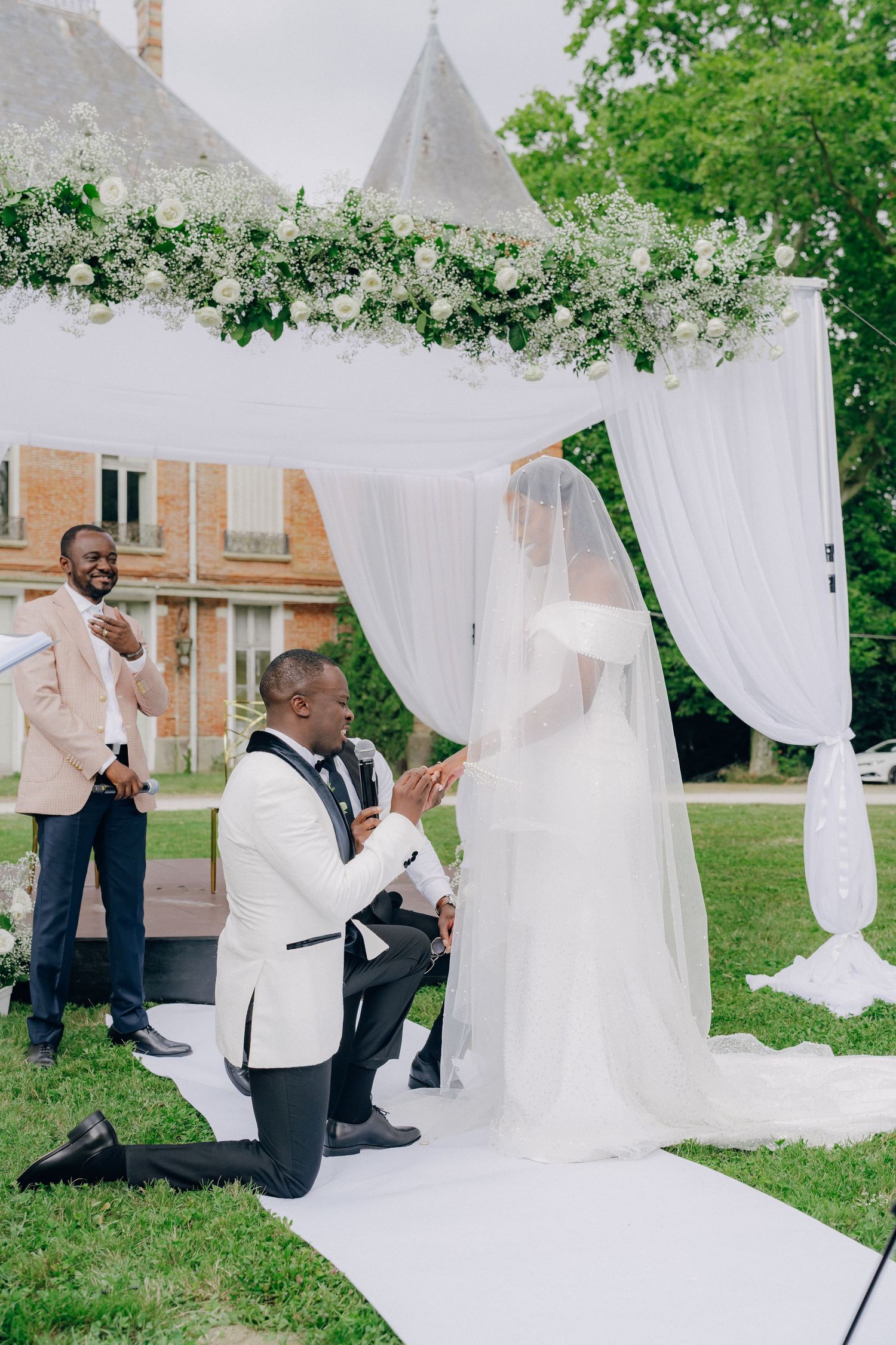 Wedding ceremony moment captured under white fabric draping outdoors.