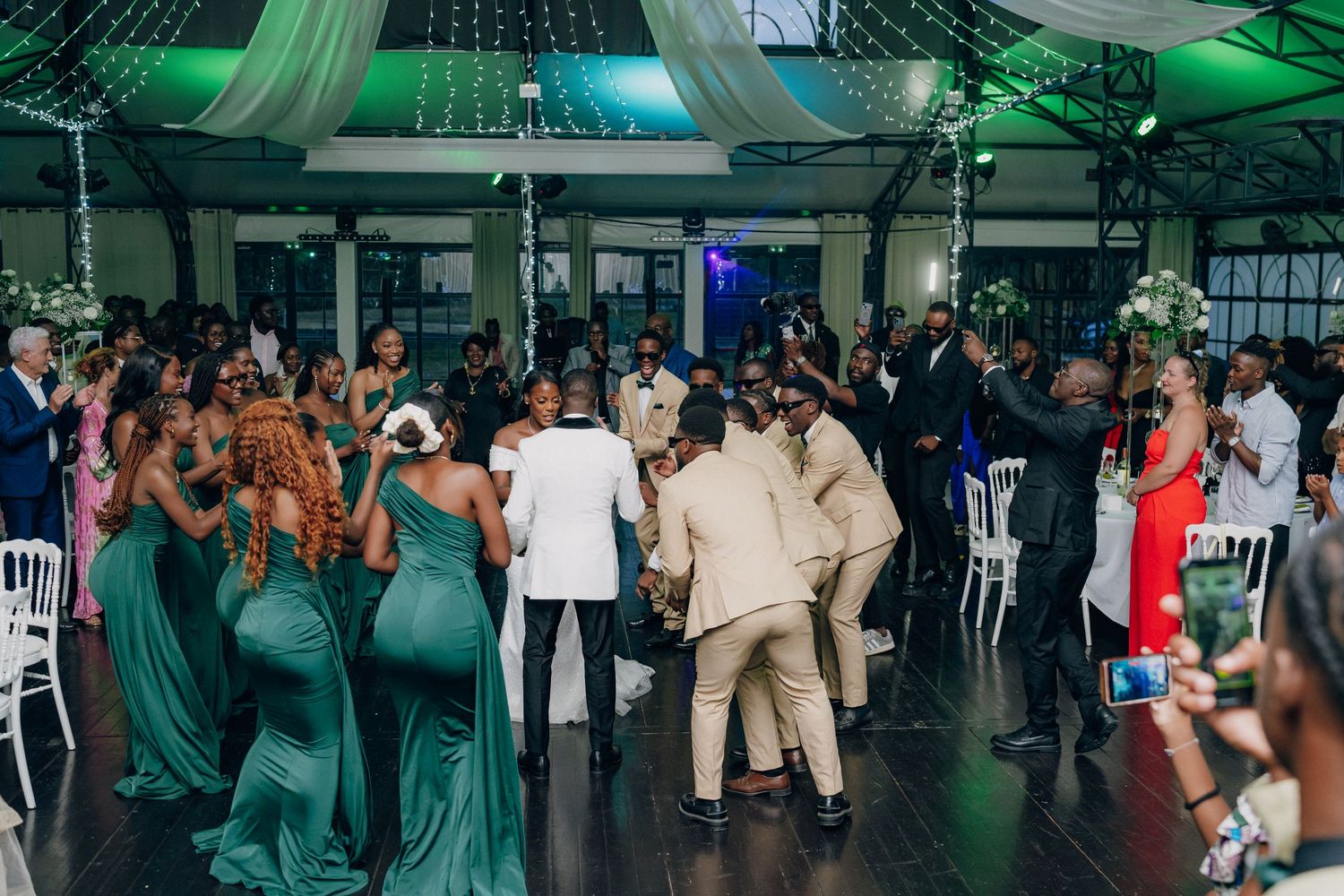 Wedding reception dance floor with emerald green decor and string lights overhead.