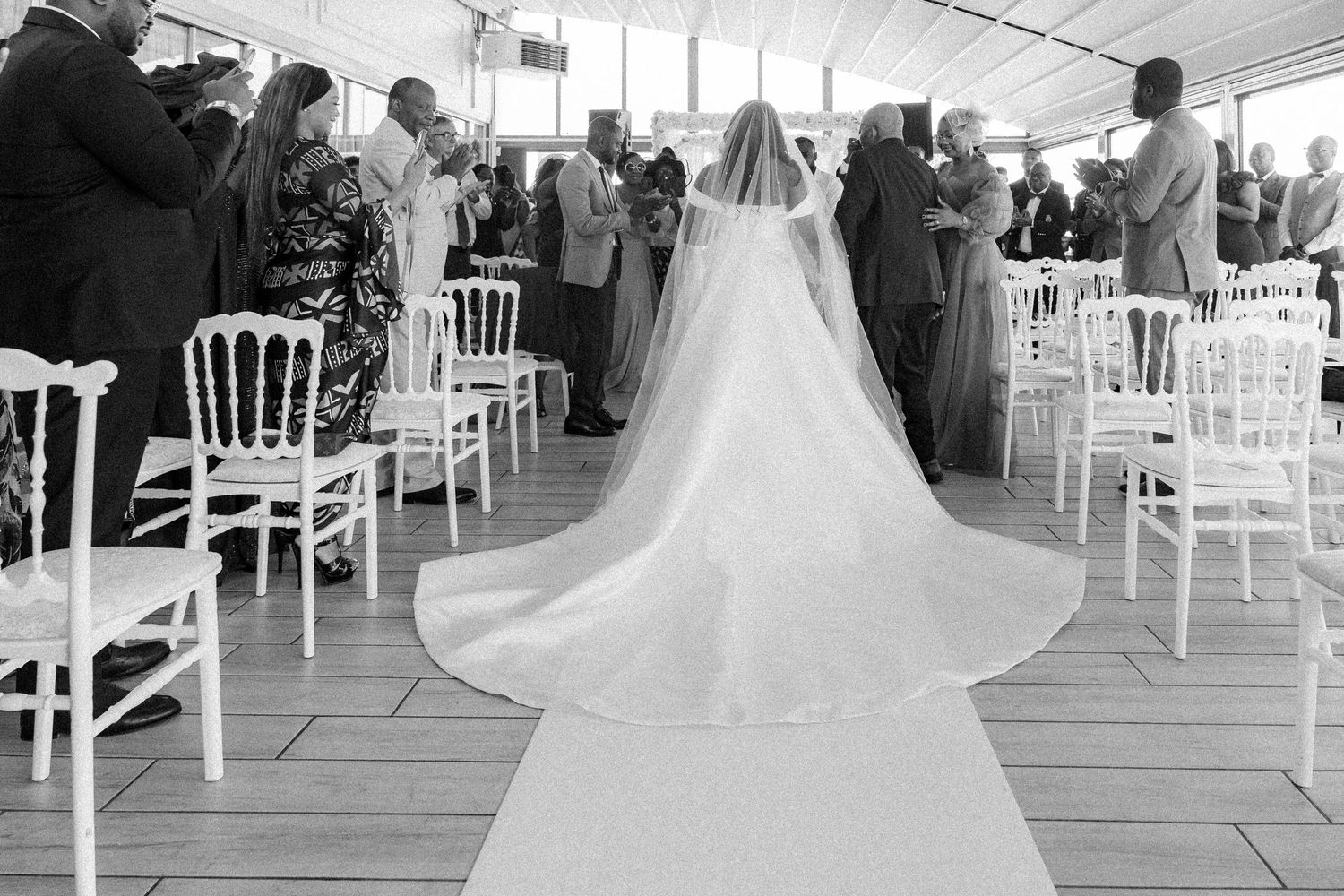 A wedding ceremony setup with elegant white chairs arranged in rows under a tent canopy.