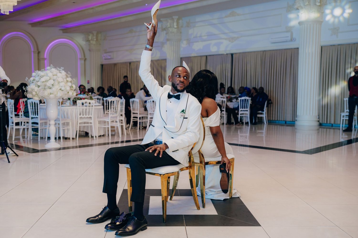 A couple performs a playful chair dance routine during their wedding reception.