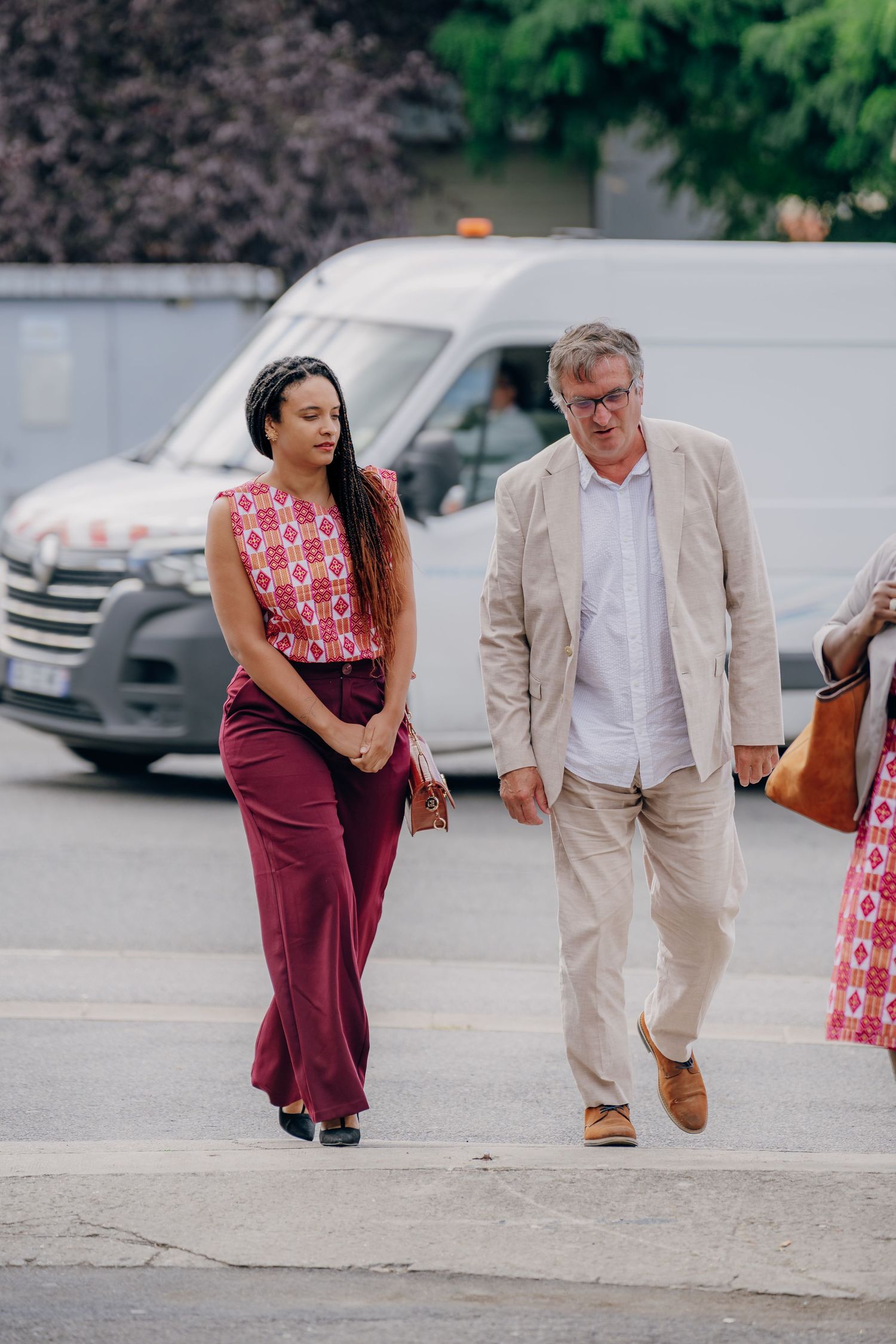 People walking together in a parking lot wearing burgundy and beige formal attire.