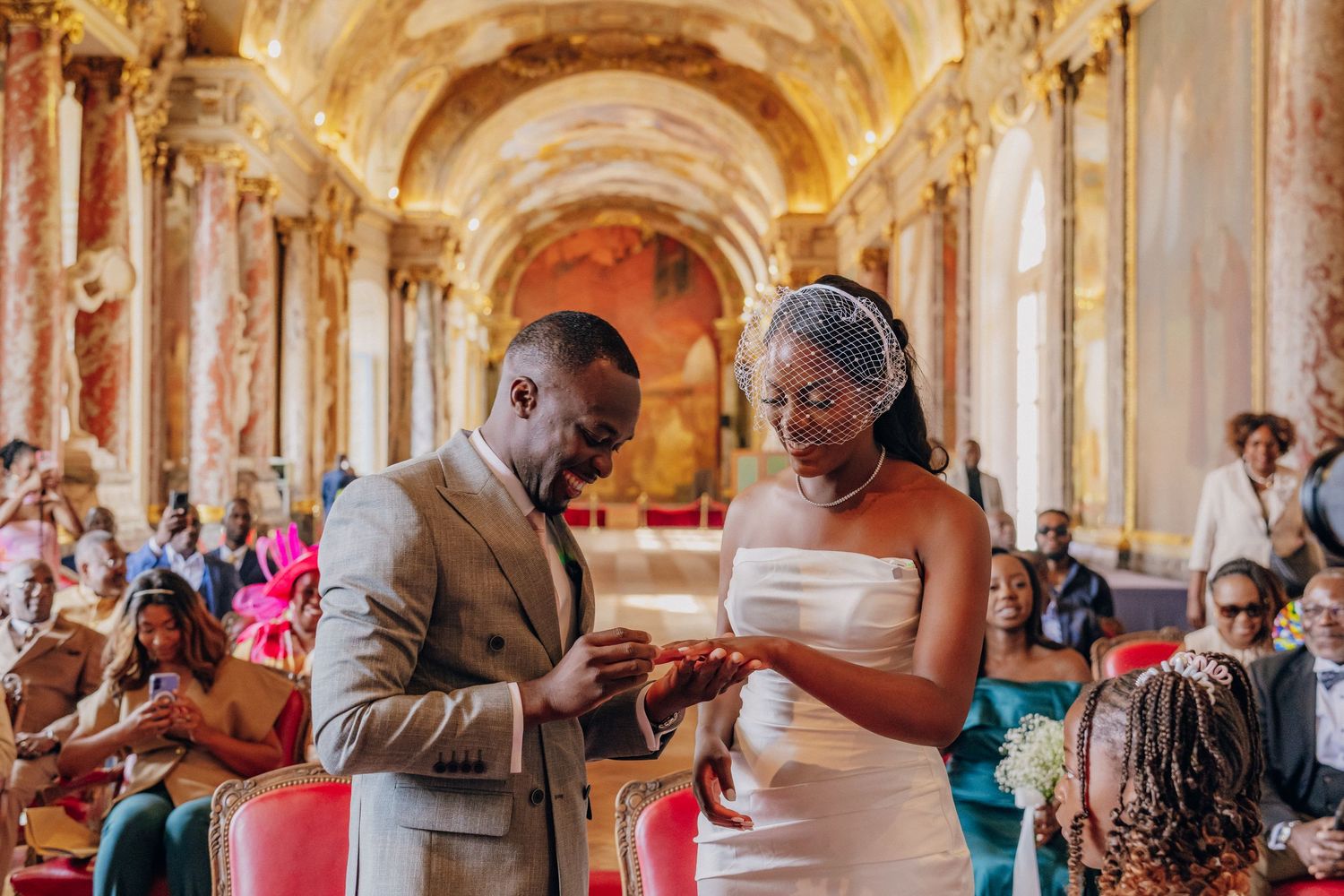 Wedding party celebrating in an elegant baroque palace corridor with frescoed walls.