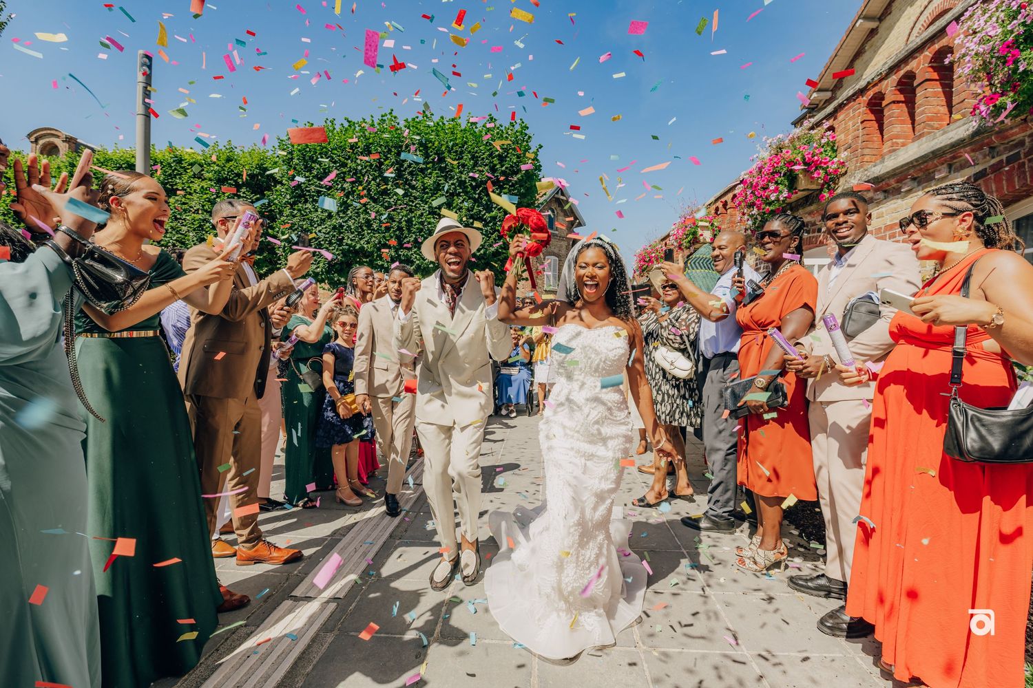 A wedding celebration with guests throwing colorful confetti petals as the newlyweds exit the church.