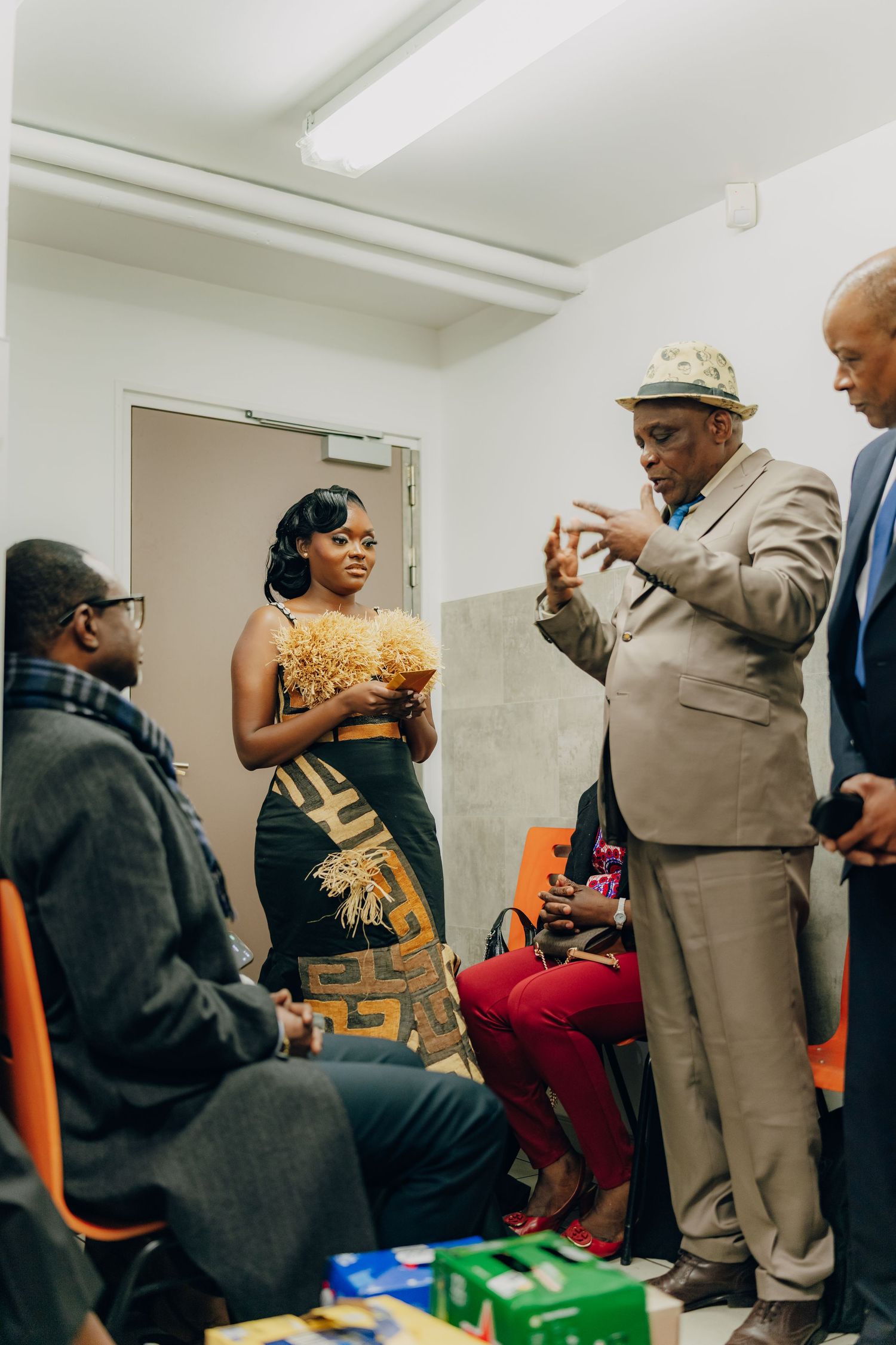 People gathered in a hallway having an animated conversation while wearing formal attire at a social event.