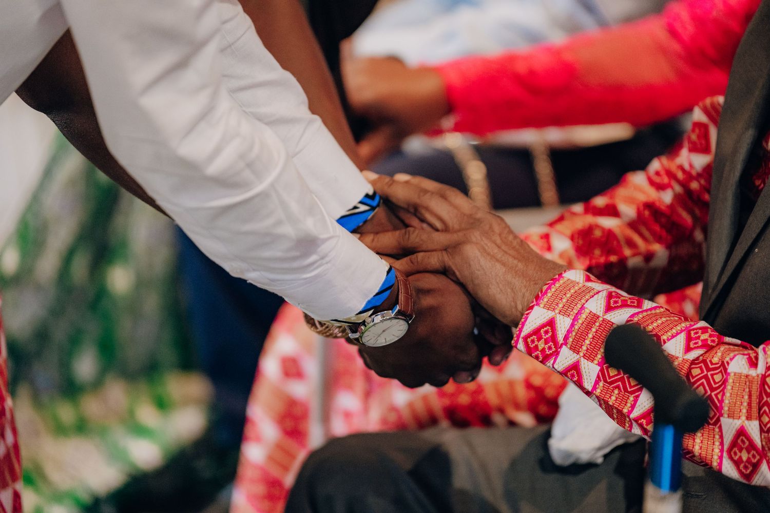Traditional Nigerian wedding celebration showing hands exchanging drinks and gifts.