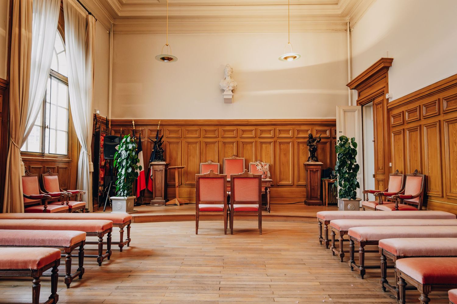 Elegant room with wooden paneling and rows of cushioned chairs arranged for a ceremony.