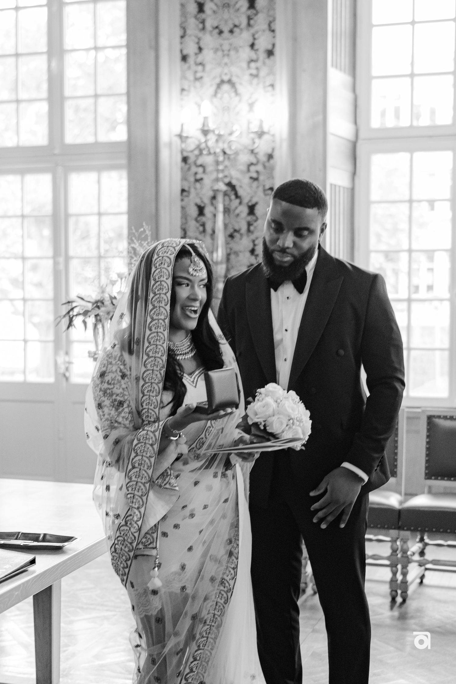 A beautiful black and white photo capturing a couple sharing a light moment in traditional wedding attire.