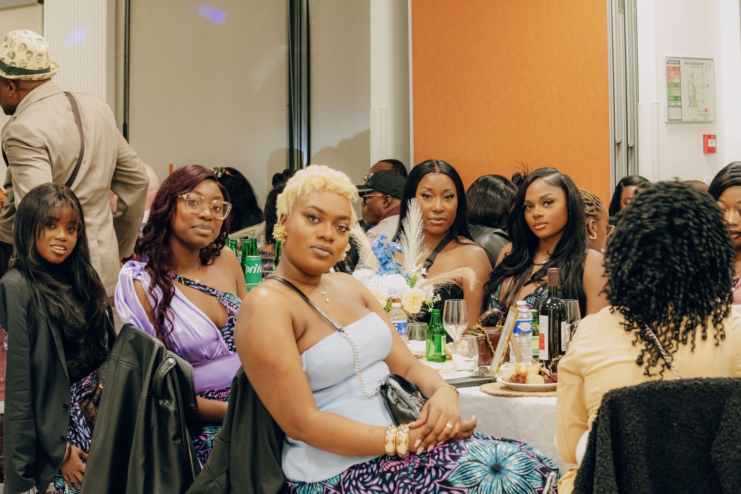 Group of stylishly dressed people gathered at social event in modern space.