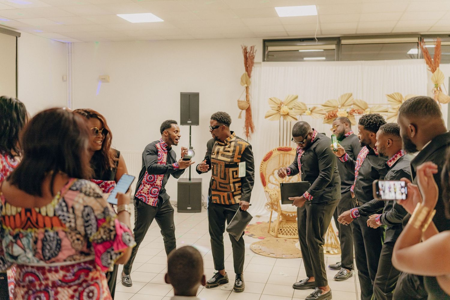 A group of people dance and celebrate at a social gathering in a brightly lit room with festive decorations.